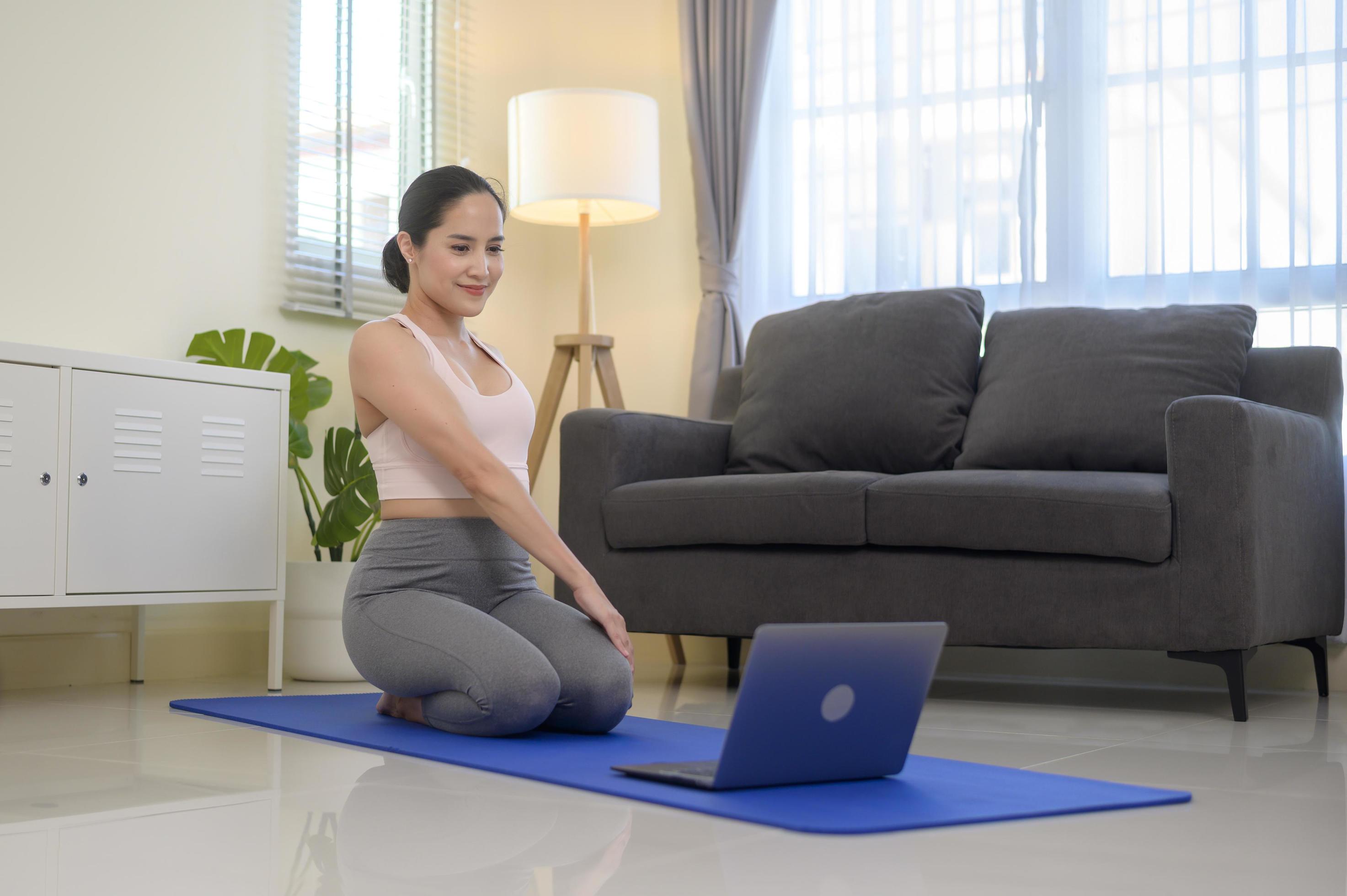 Fit young woman practicing yoga at home via online class with professional instructor, sport and healthy lifestyle concept. Stock Free