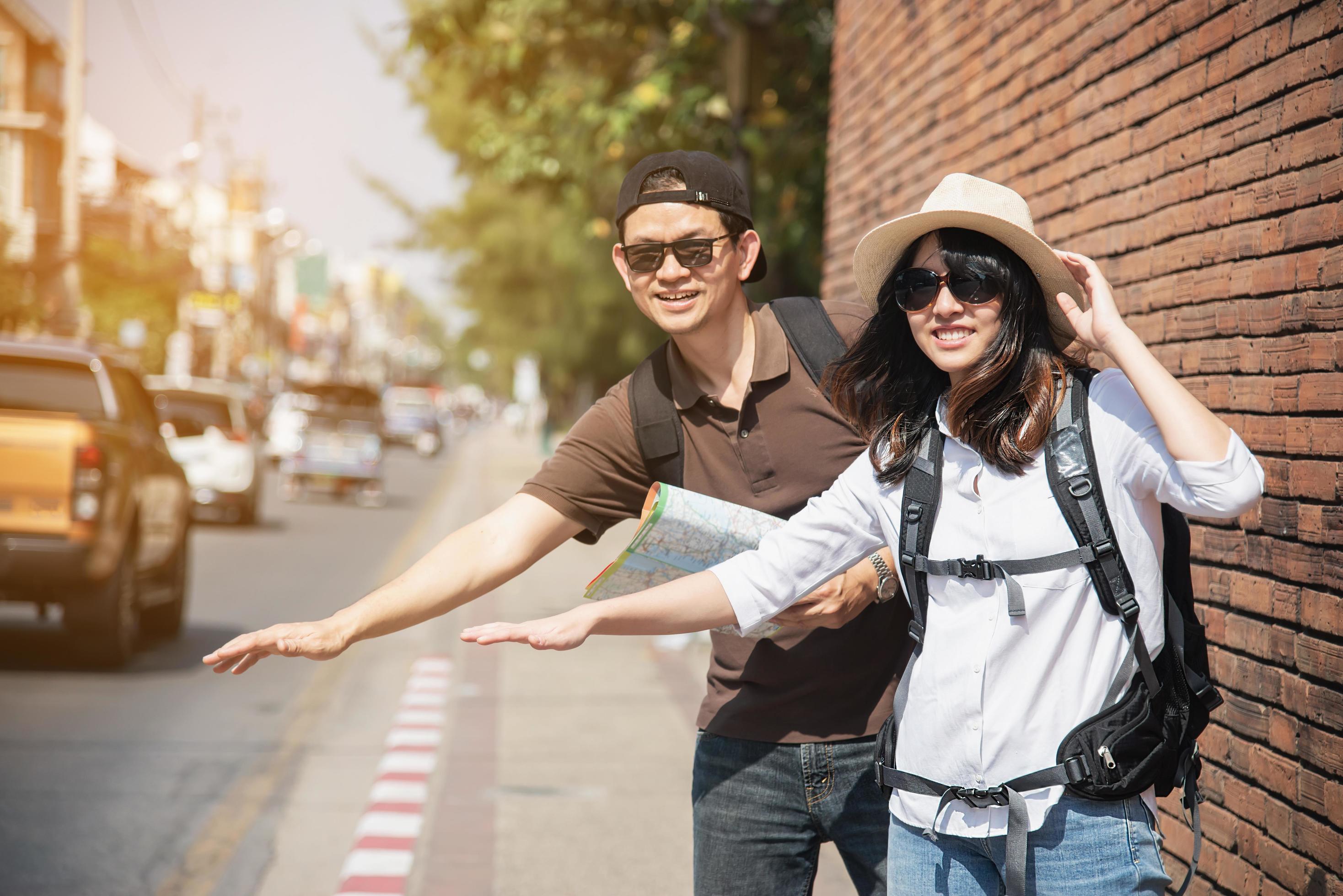 Asian backpack couple tourist holding city map crossing the road – travel people vacation lifestyle concept Stock Free