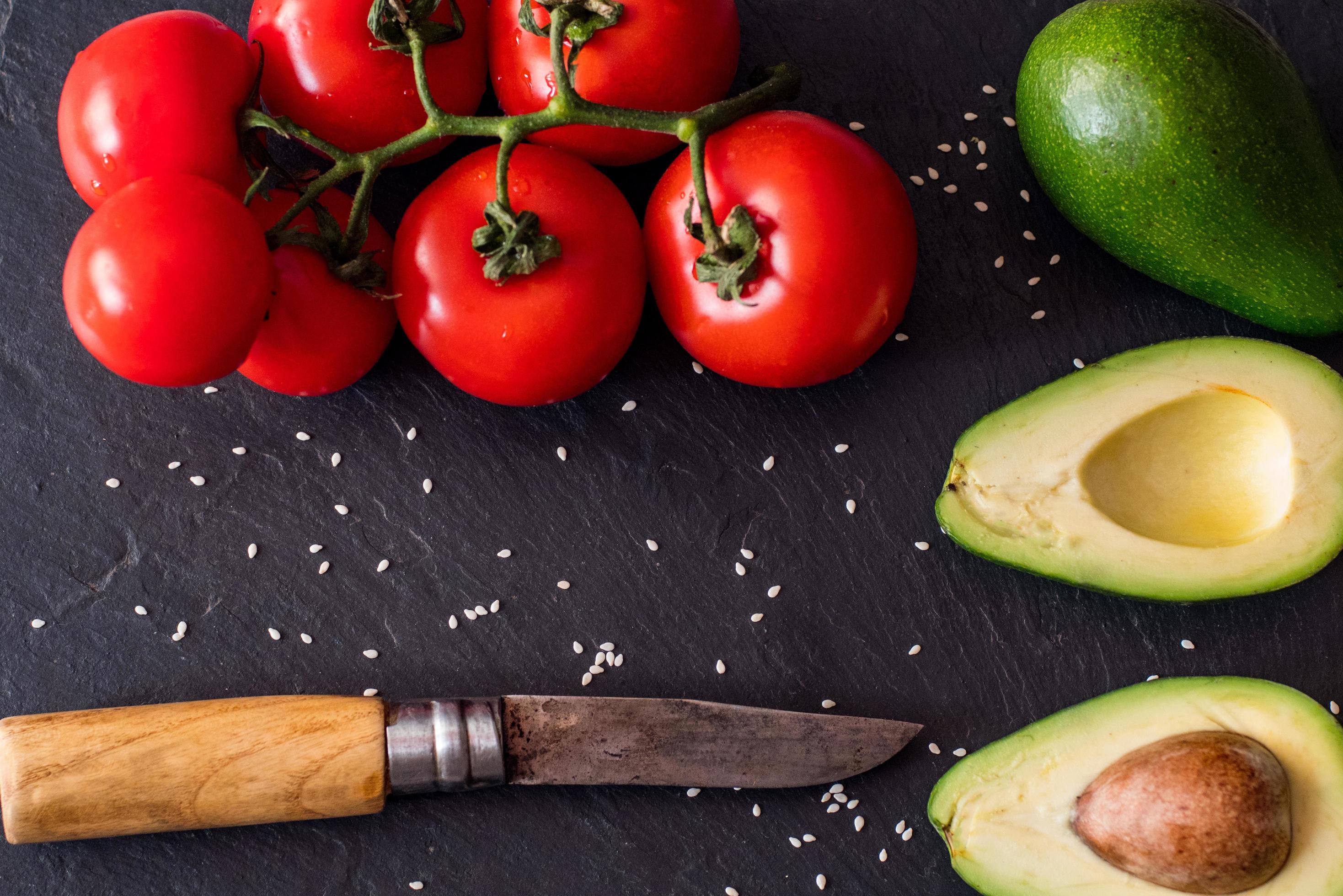 Tomatos and avocado on black table close up, colorful healthy food Stock Free