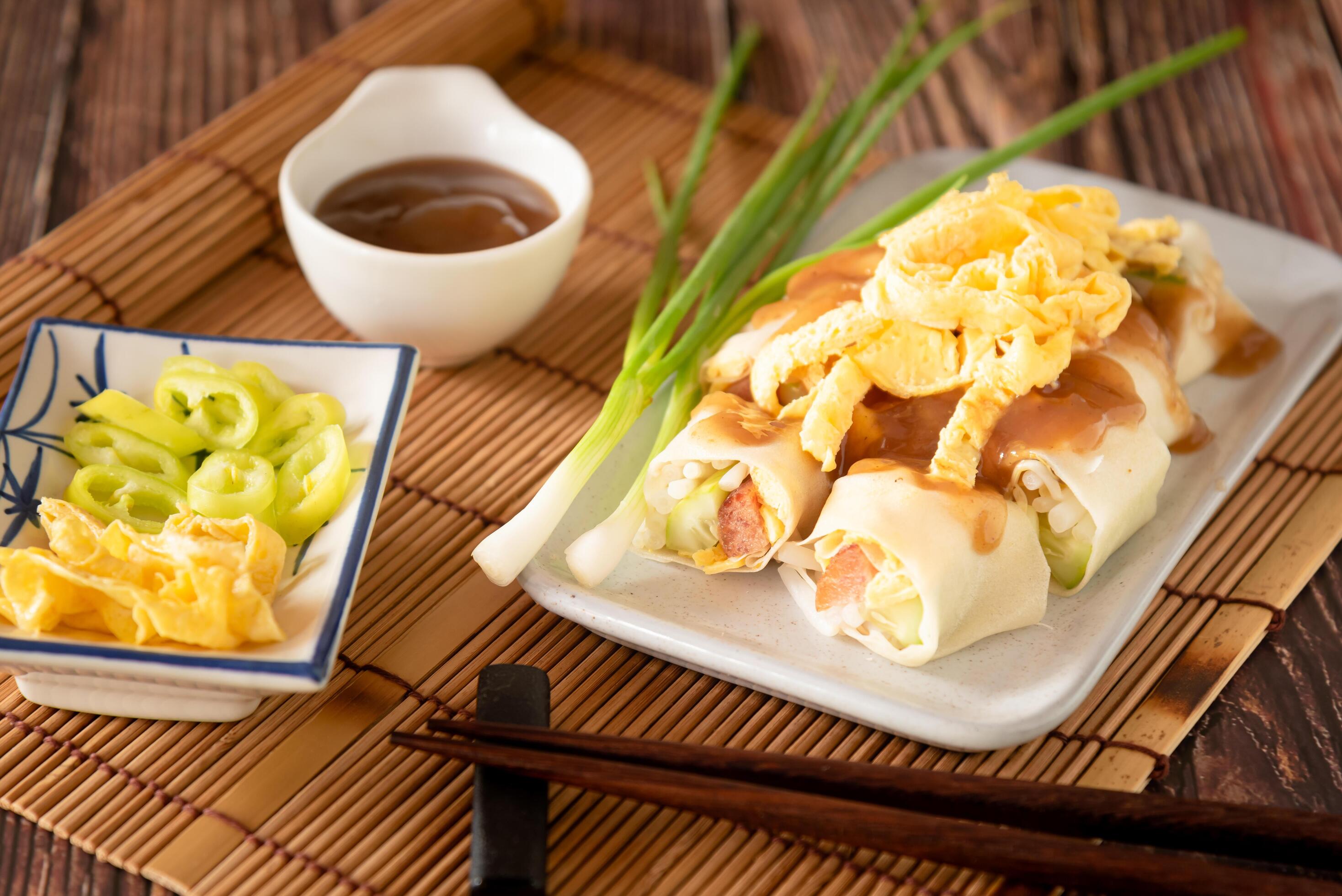 Thai traditional fresh spring roll with sweet sauce, stuff vegetable and sweet sausage on wooden background Stock Free