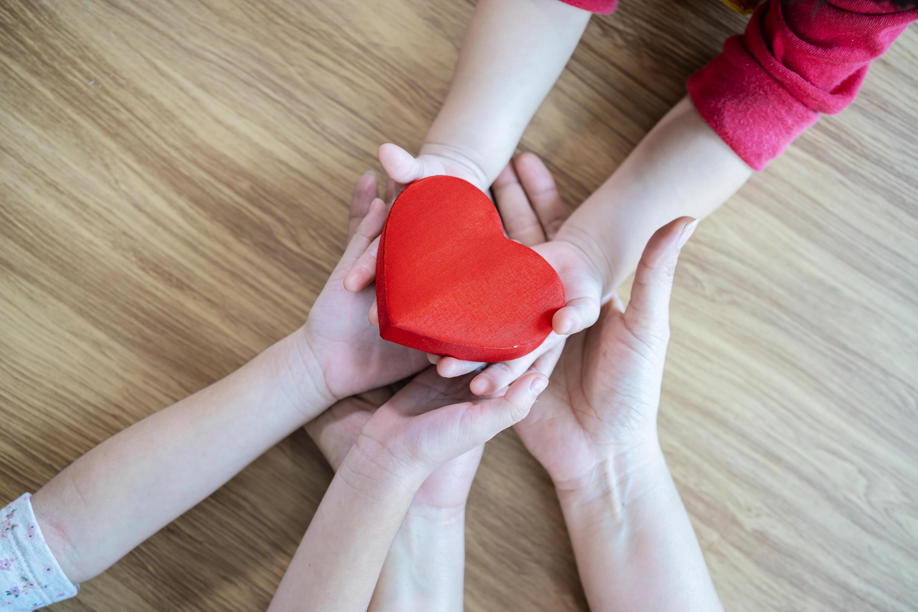 adult and child hands holding red heart on aqua background, heart health, donation, CSR concept, world heart day, world health day, family day Stock Free