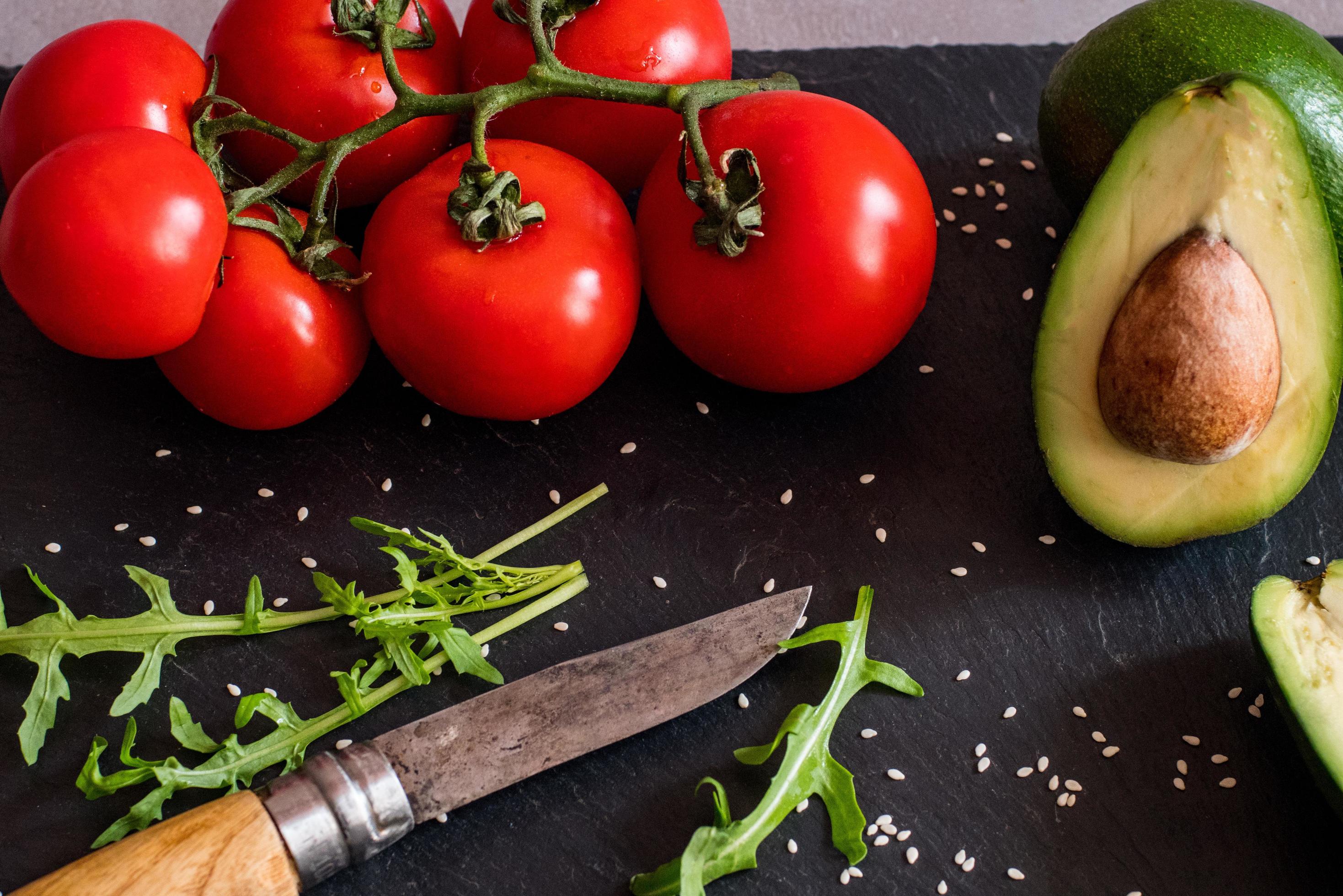 Tomatos and avocado on black table close up, colorful healthy food Stock Free