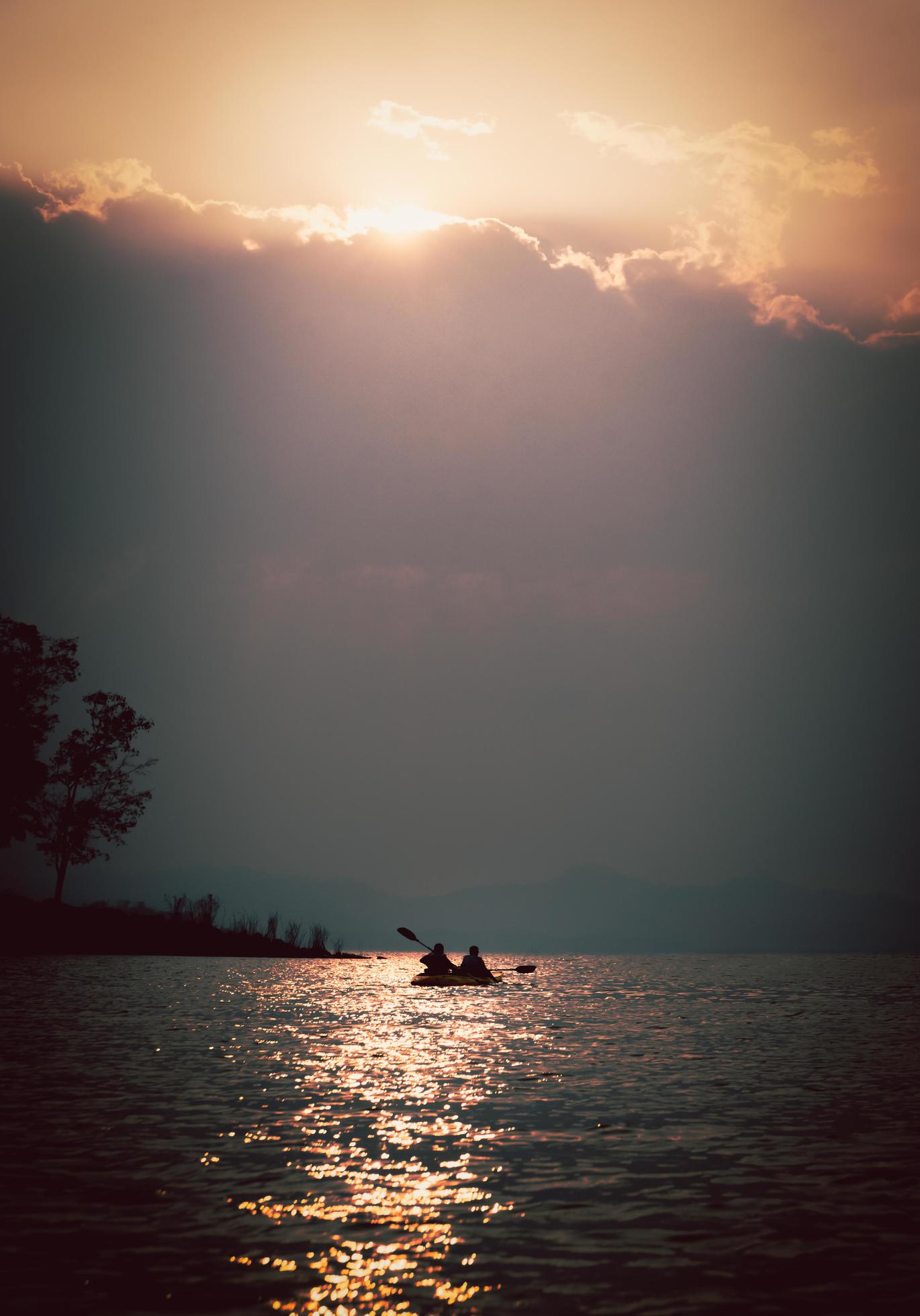 Silhouettes of people in kayak at sunset. Stock Free