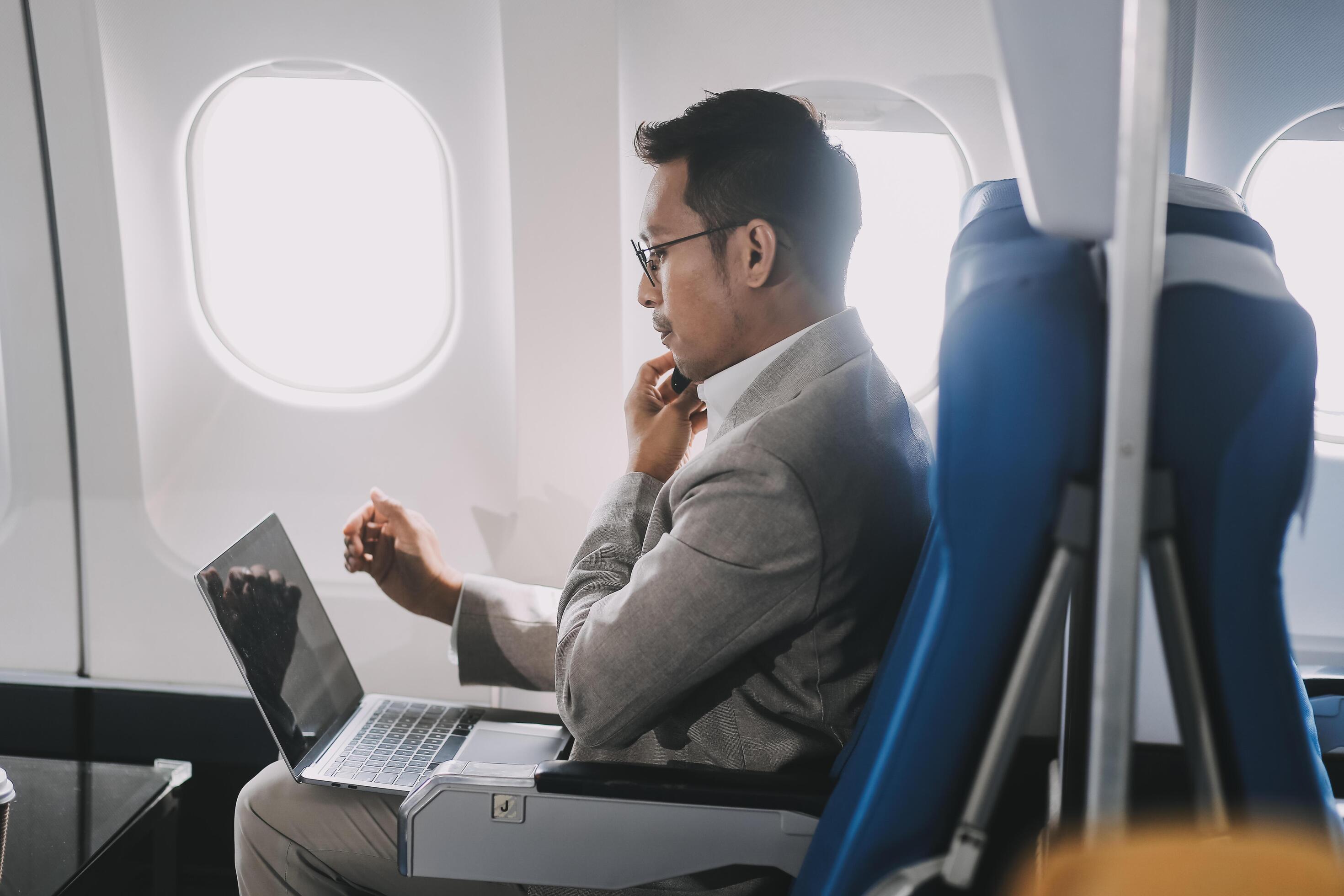 Asian businessman enjoying enjoys a coffee comfortable flight while sitting in the airplane cabin, Passengers near the window. Stock Free