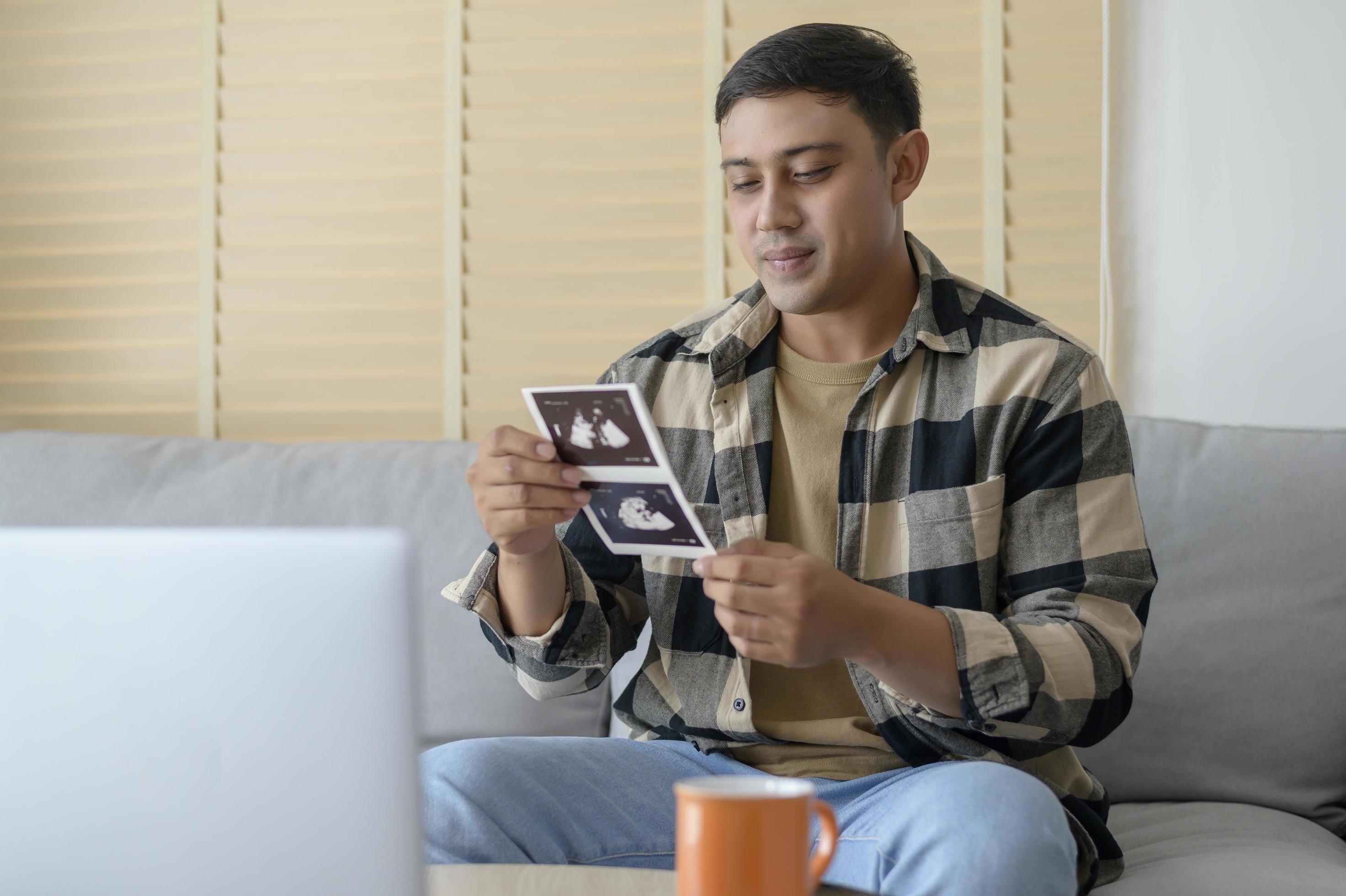 Young father holding ultrasound photo of newborn baby, maternity and family concept Stock Free