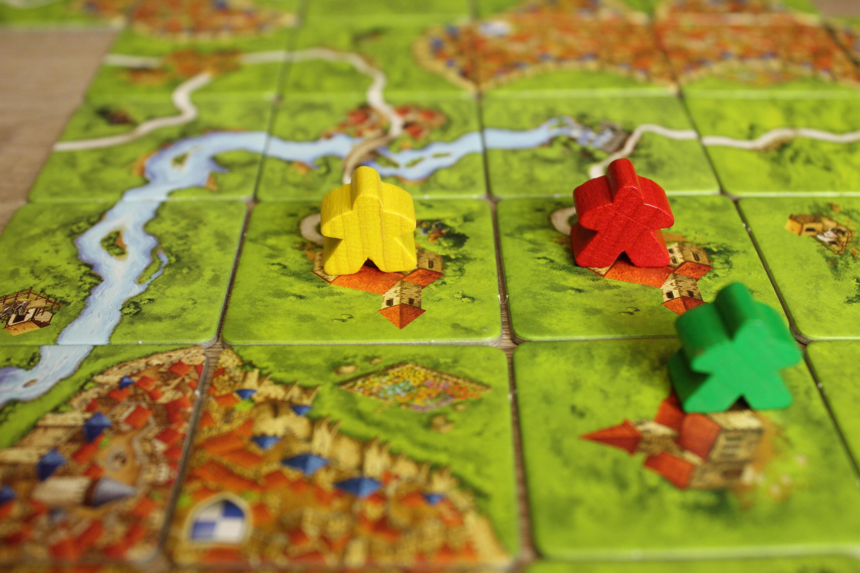 board family game carcassonne green yellow red meeple on the map tiles of the playing field. Rules for placing monasteries on carriages Stock Free