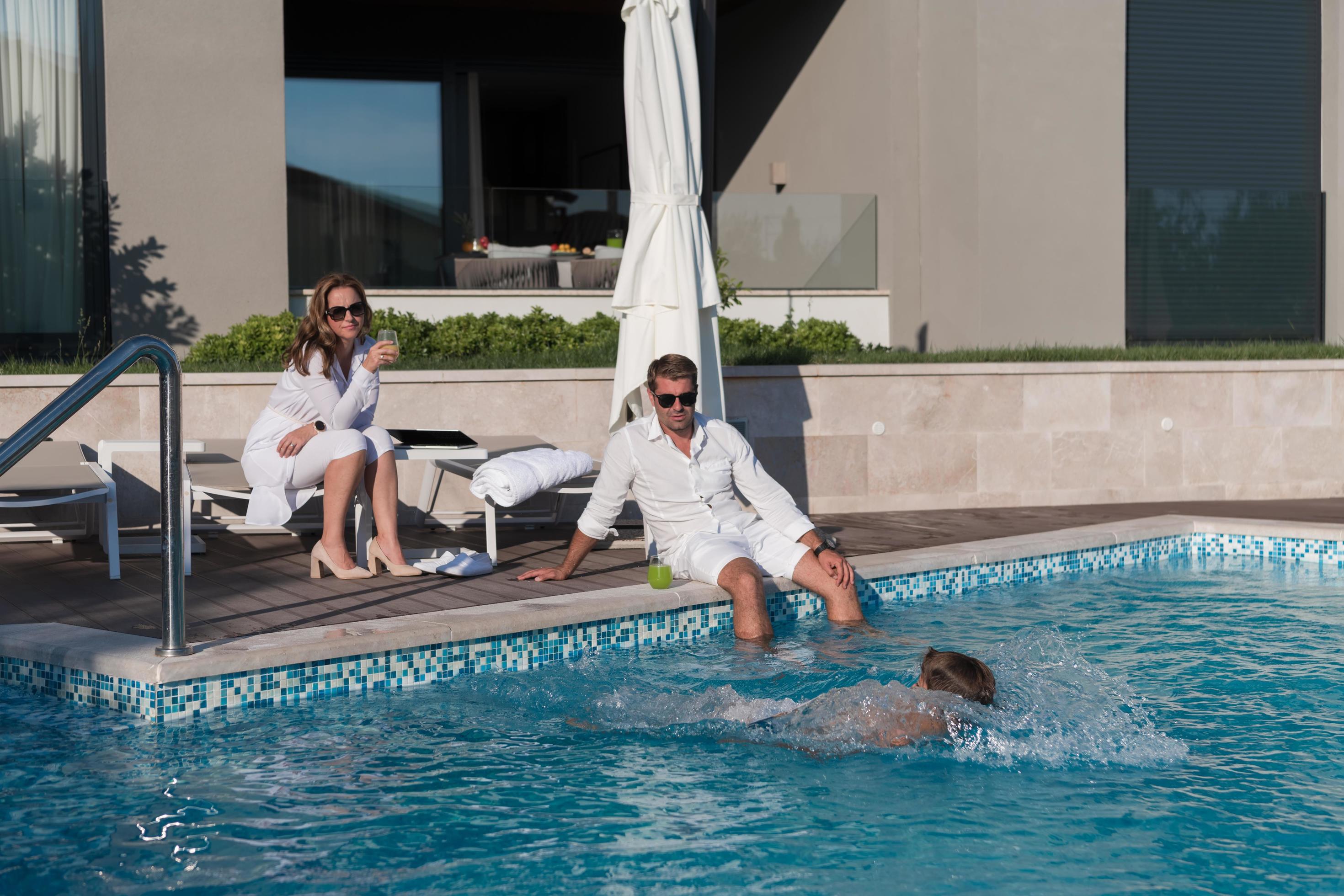 Happy family enjoys vacation in a luxury house with pool. Senior couple spends time with their son during the vacation. Selective focus Stock Free