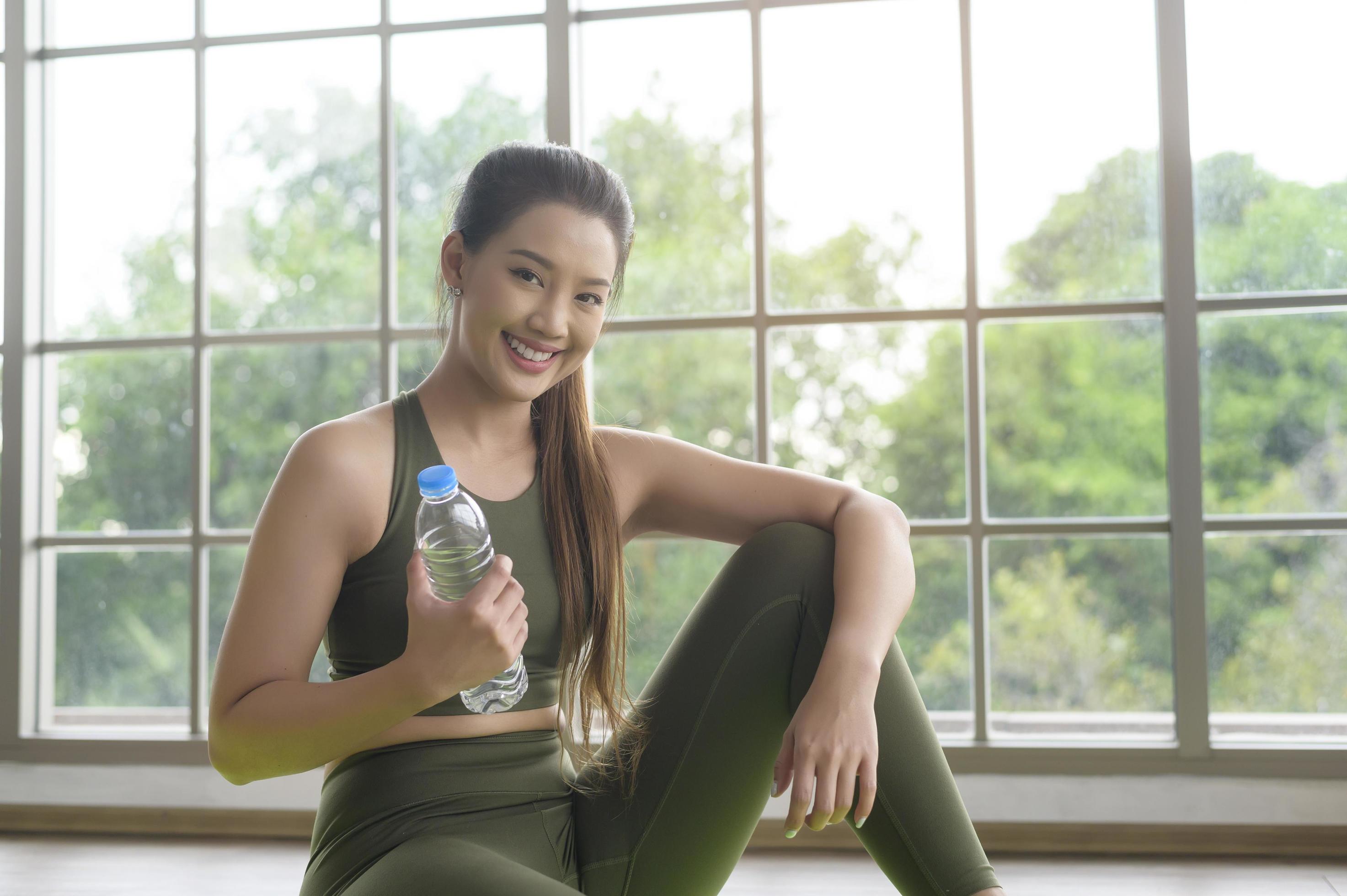 Young fitness woman in sportswear drinking water after exercising at home, Healthy and Lifestyles. Stock Free