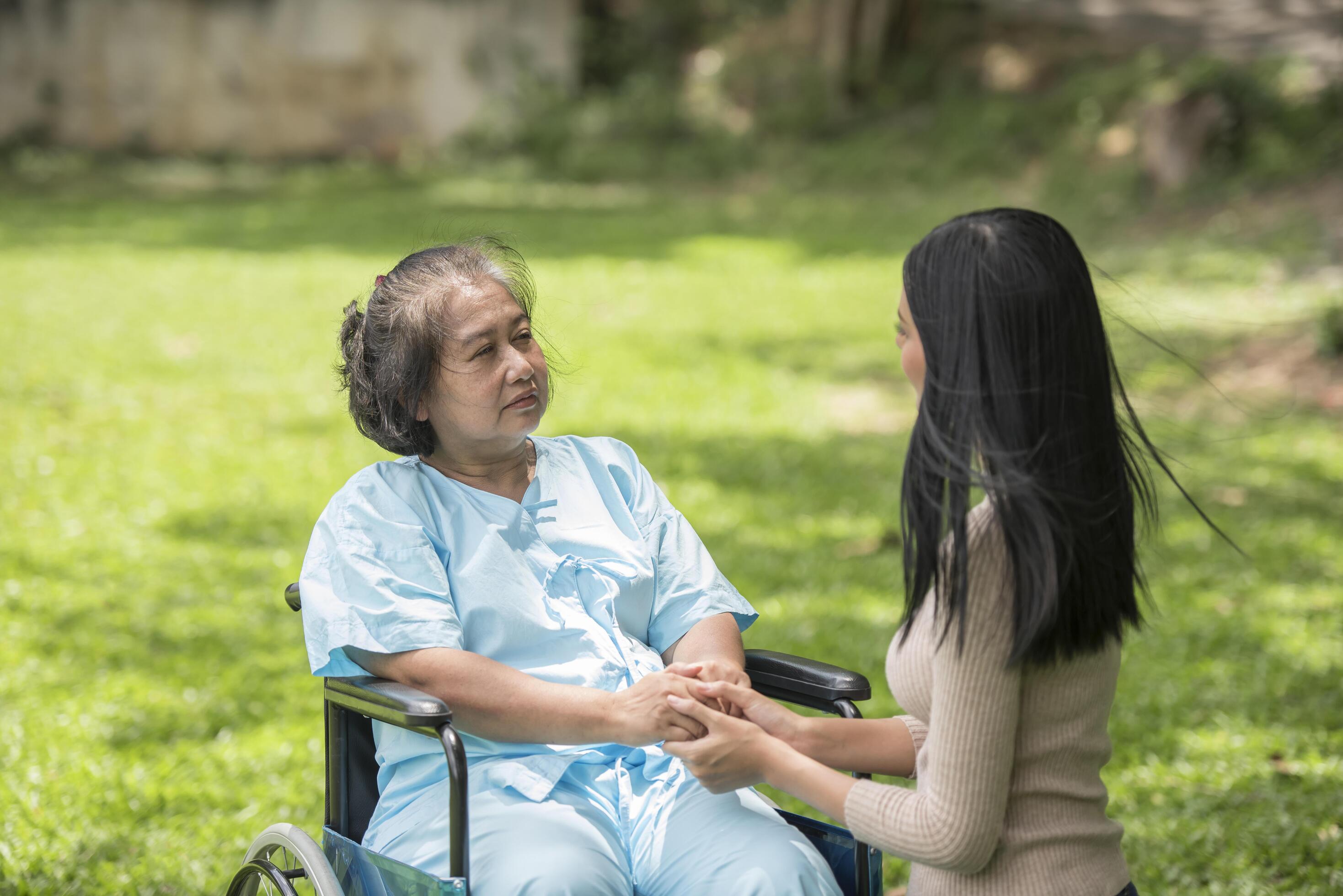 Granddaughter talking with her grandmother sitting on wheelchair, cheerful concept, happy family Stock Free