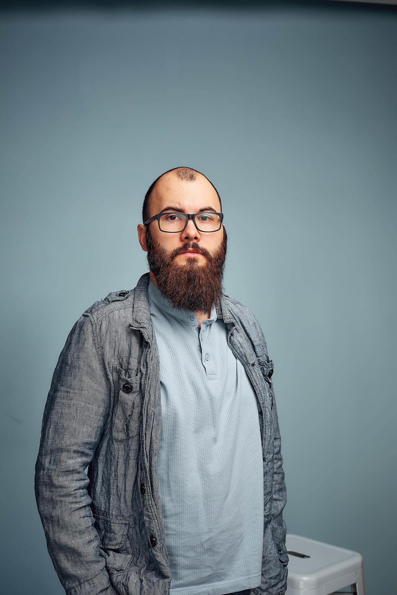 lifestyle successful young man with glasses , beard, fashionable denim jacket looking forward,male portrait in the Studio on a uniform background. Stock Free