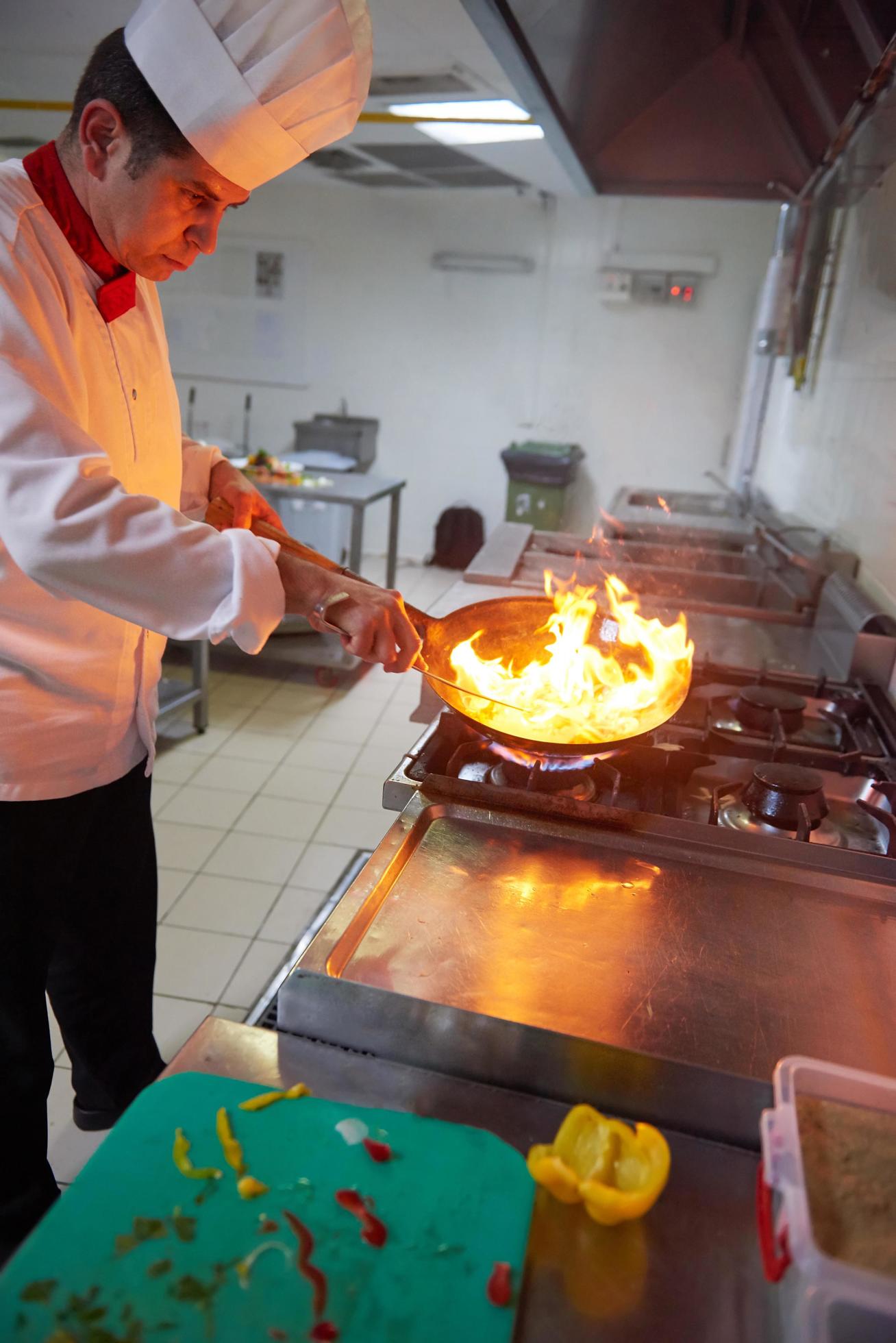 chef in hotel kitchen prepare food with fire Stock Free