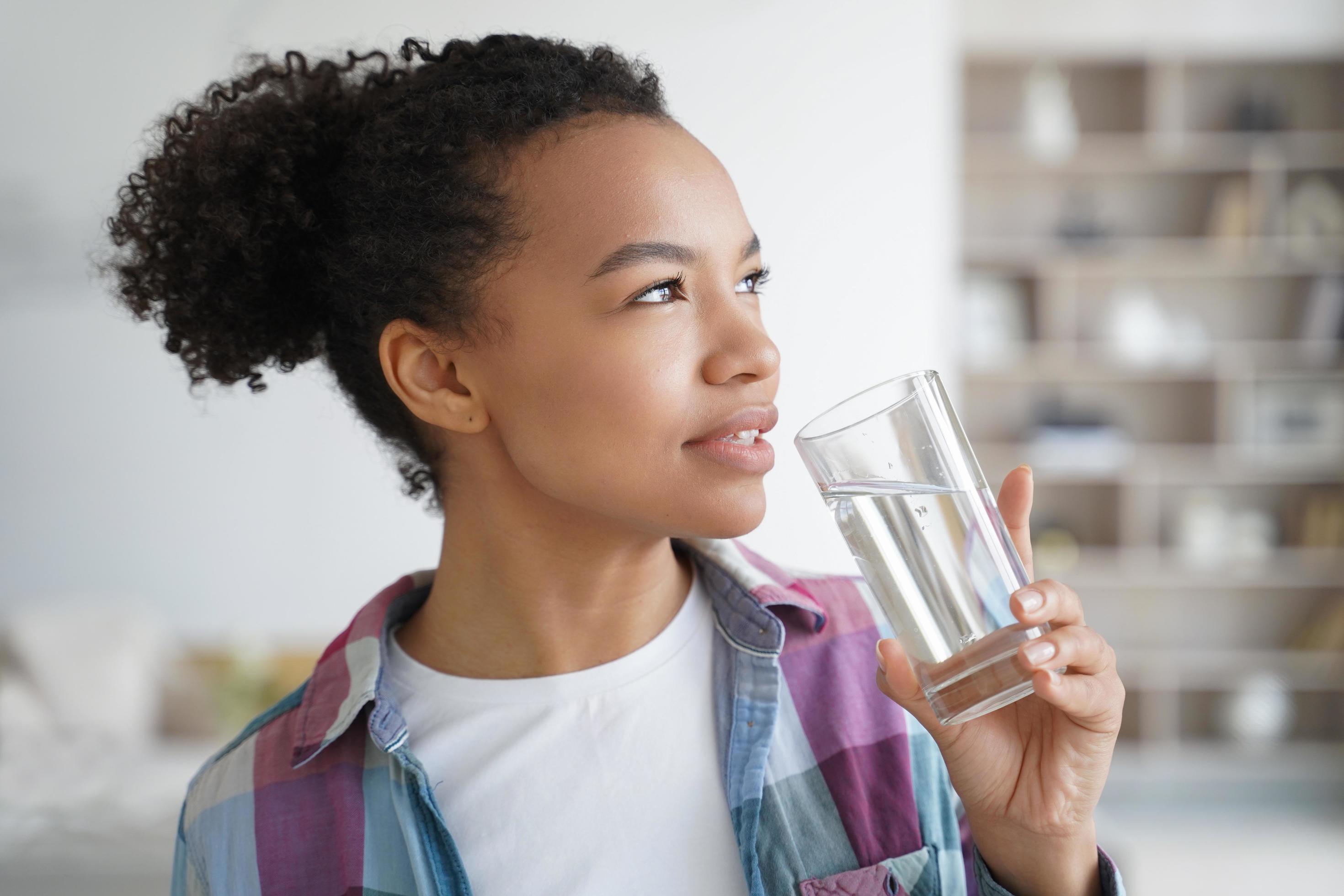 Lovely young hispanic woman enjoying mineral water. Healthy lifestyle, fitness and wellness. Stock Free