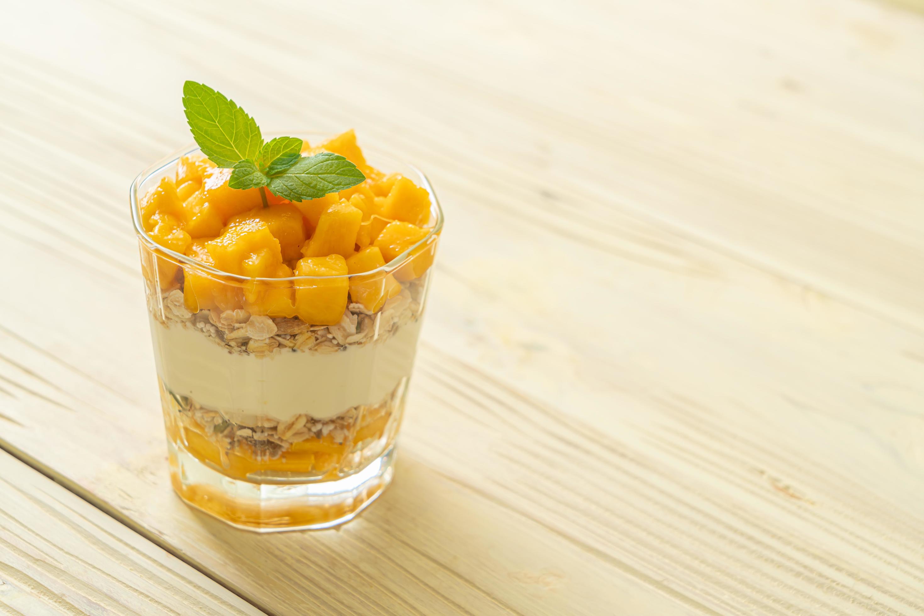 Fresh mango yogurt with granola in glass – healthy food style Stock Free