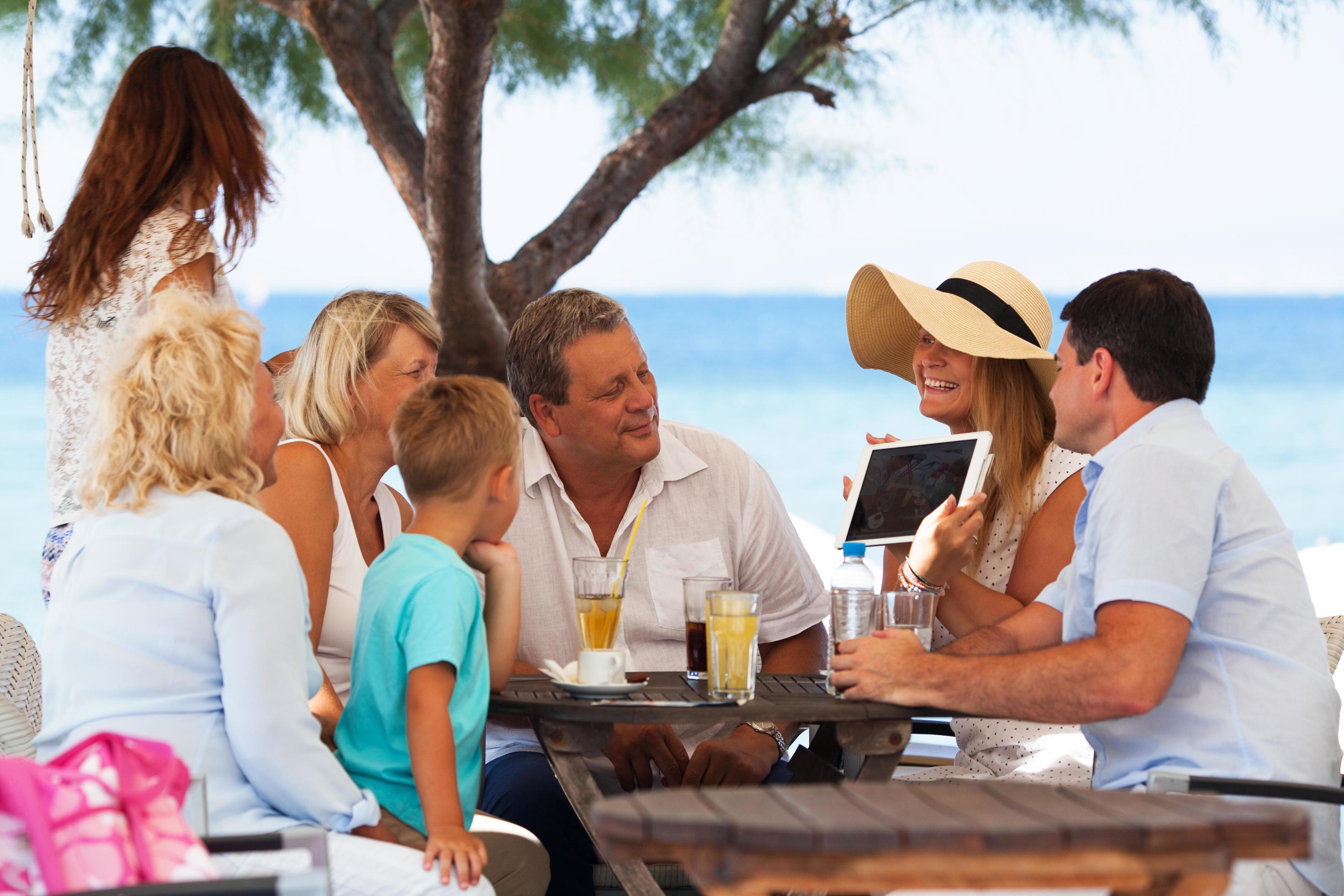 Family looking at photo on a tablet in an outdoor cafe Stock Free