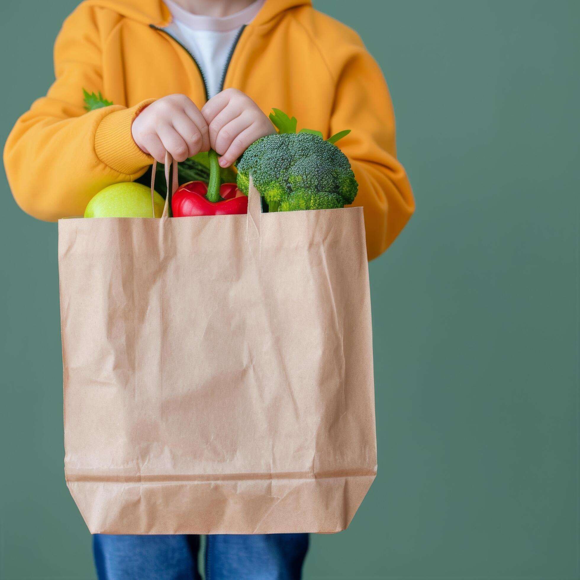 Fresh Vegetables and Greens in Brown Paper Bag Held by Person Against Light Background Stock Free