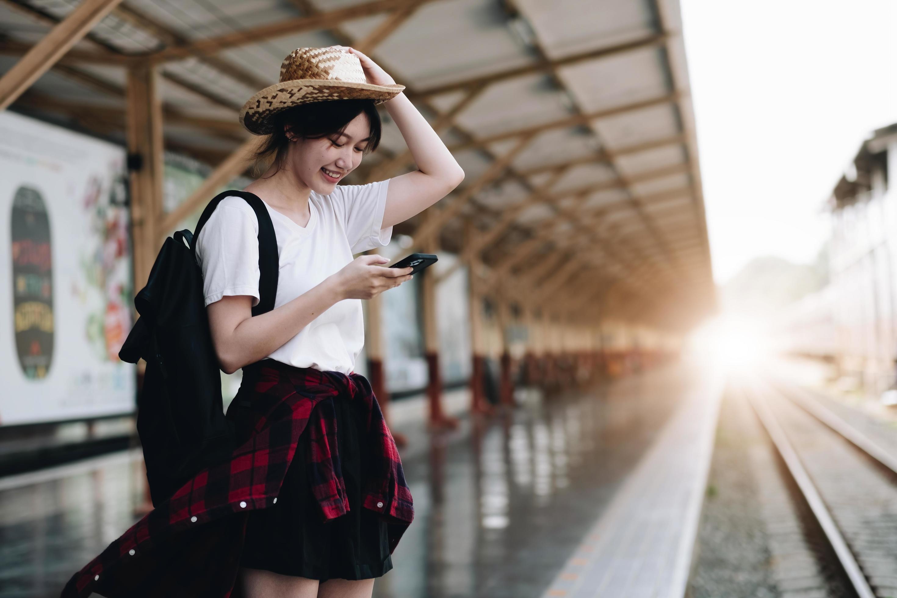 Young traveler woman looking for friend planning trip at train station. Summer and travel lifestyle concept Stock Free