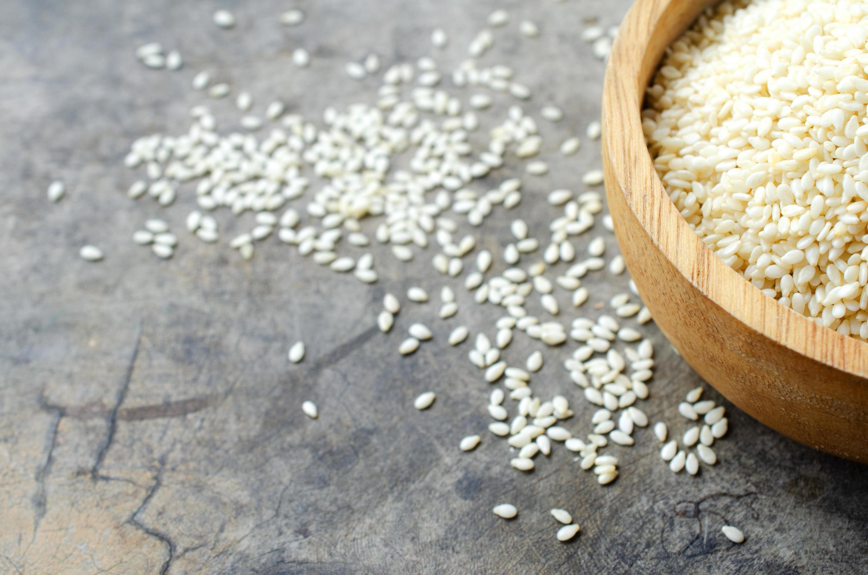 Close up of white sesame seeds in wooden bowl for raw food backgrounds Stock Free