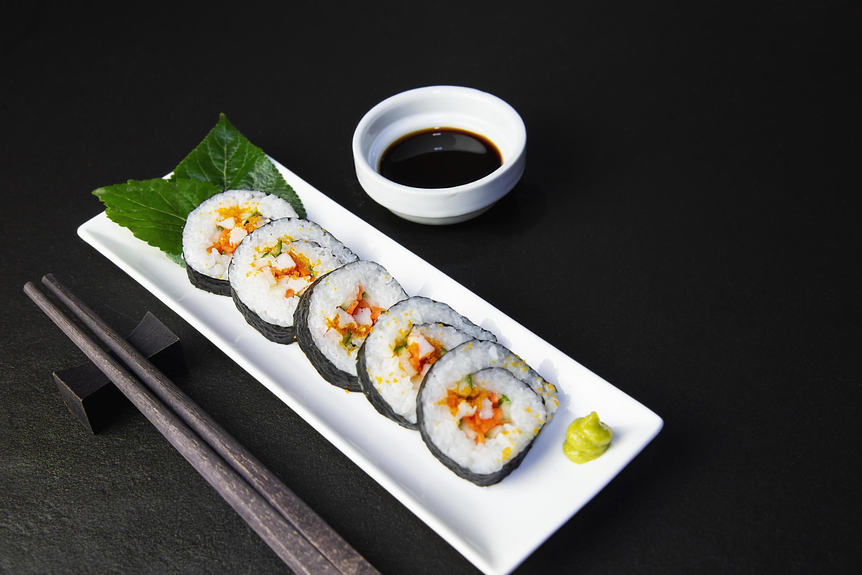 Sushi roll set serving on white plate over black table background – favorite dish Japanese food concept Stock Free