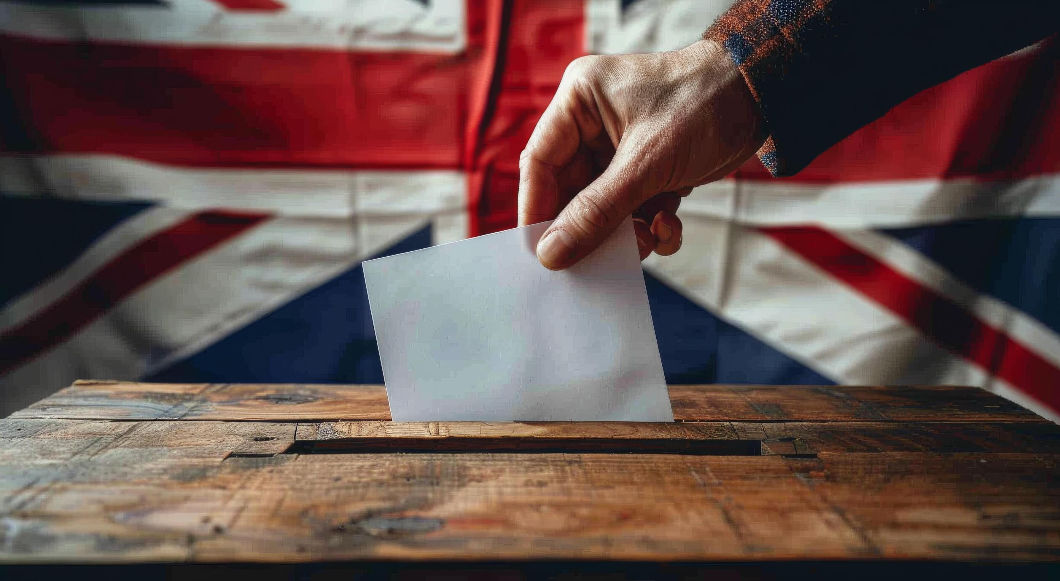 Hand Placing Ballot in Wooden Box With UK Flag Background Stock Free