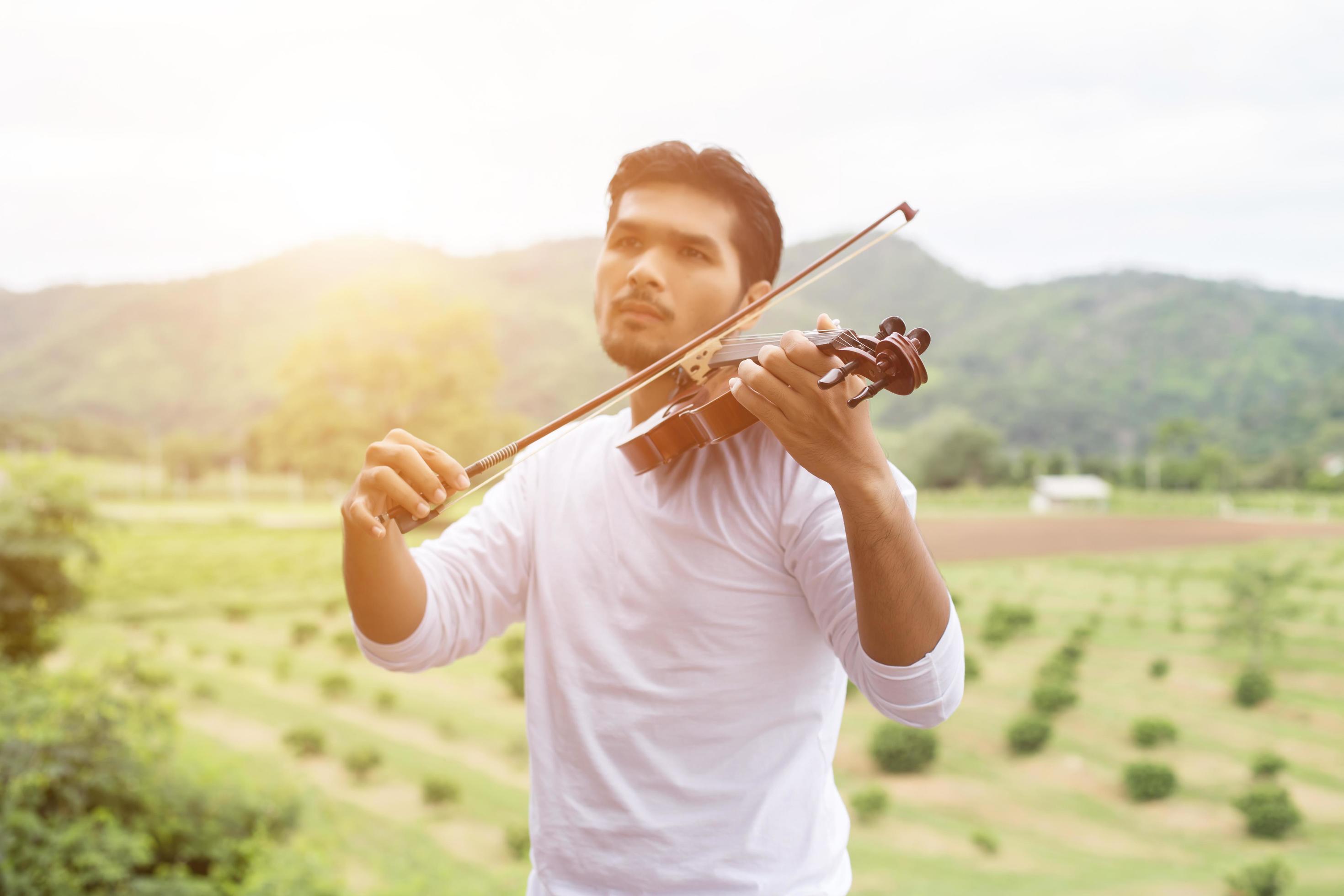 Young hipster musician man playing violin in the nature outdoor lifestyle behind mountain. Stock Free