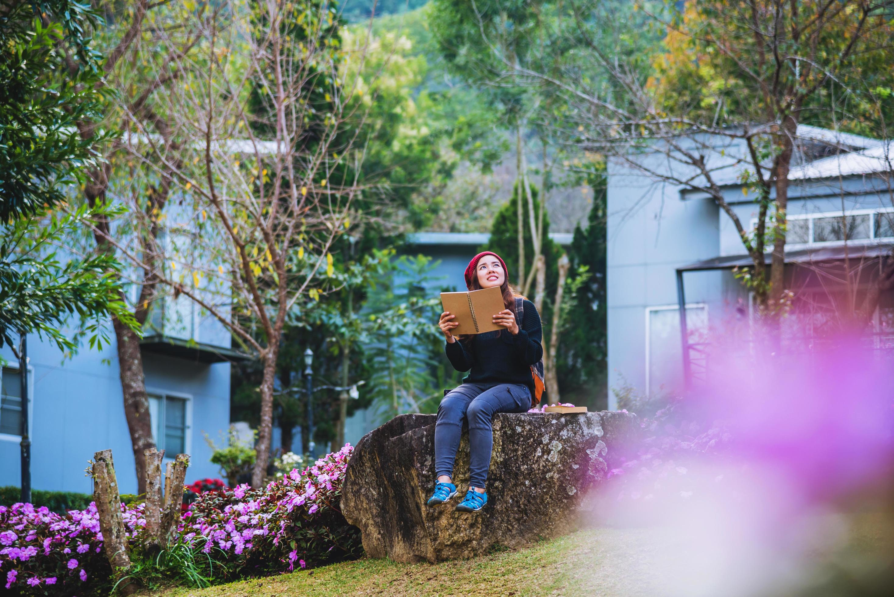 woman travel nature in the flower garden. relax sitting on rocks and reading books In the midst of nature at national park doi Inthanon. Stock Free