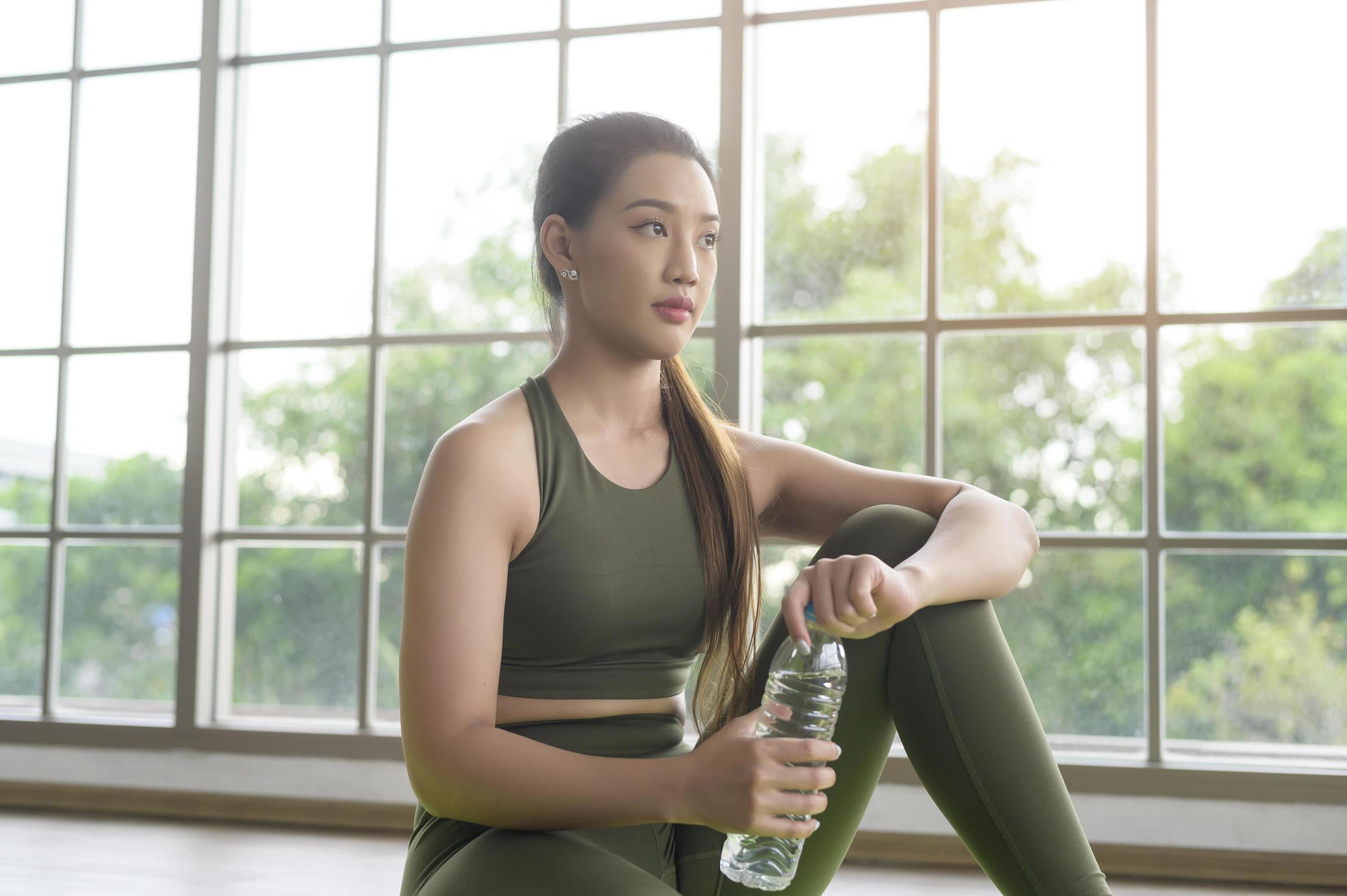 Young fitness woman in sportswear drinking water after exercising at home, Healthy and Lifestyles. Stock Free