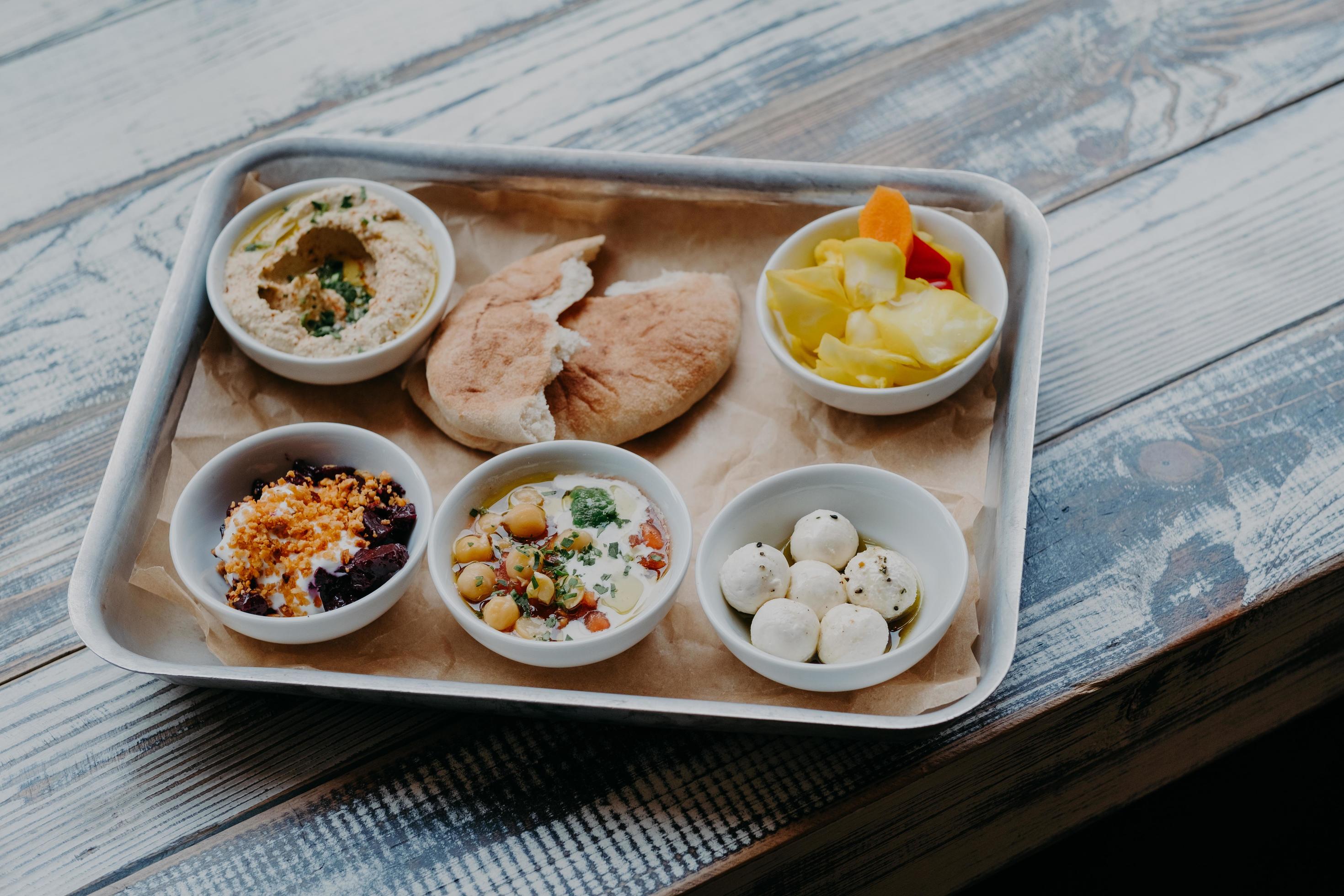 Traditional Israel food concept. Bowl of exotic dish on tray. Hummus, vegetables with spices. Pita bread. Delicious breakfast. Goat cheese. Stock Free