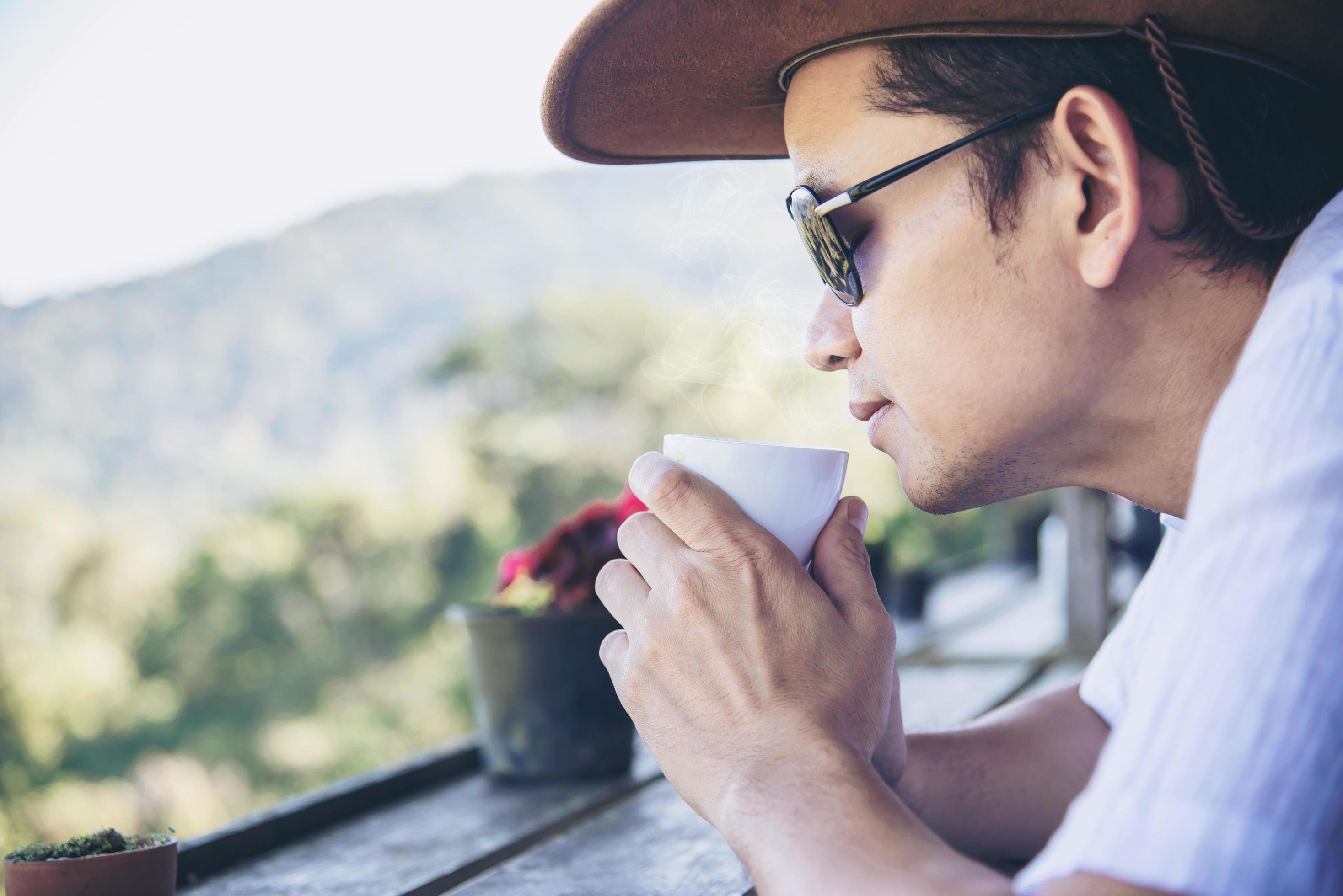 Relax Asian man drink coffee and read book in a modern style coffee shop – people with coffee cup easy lifestyle concept Stock Free