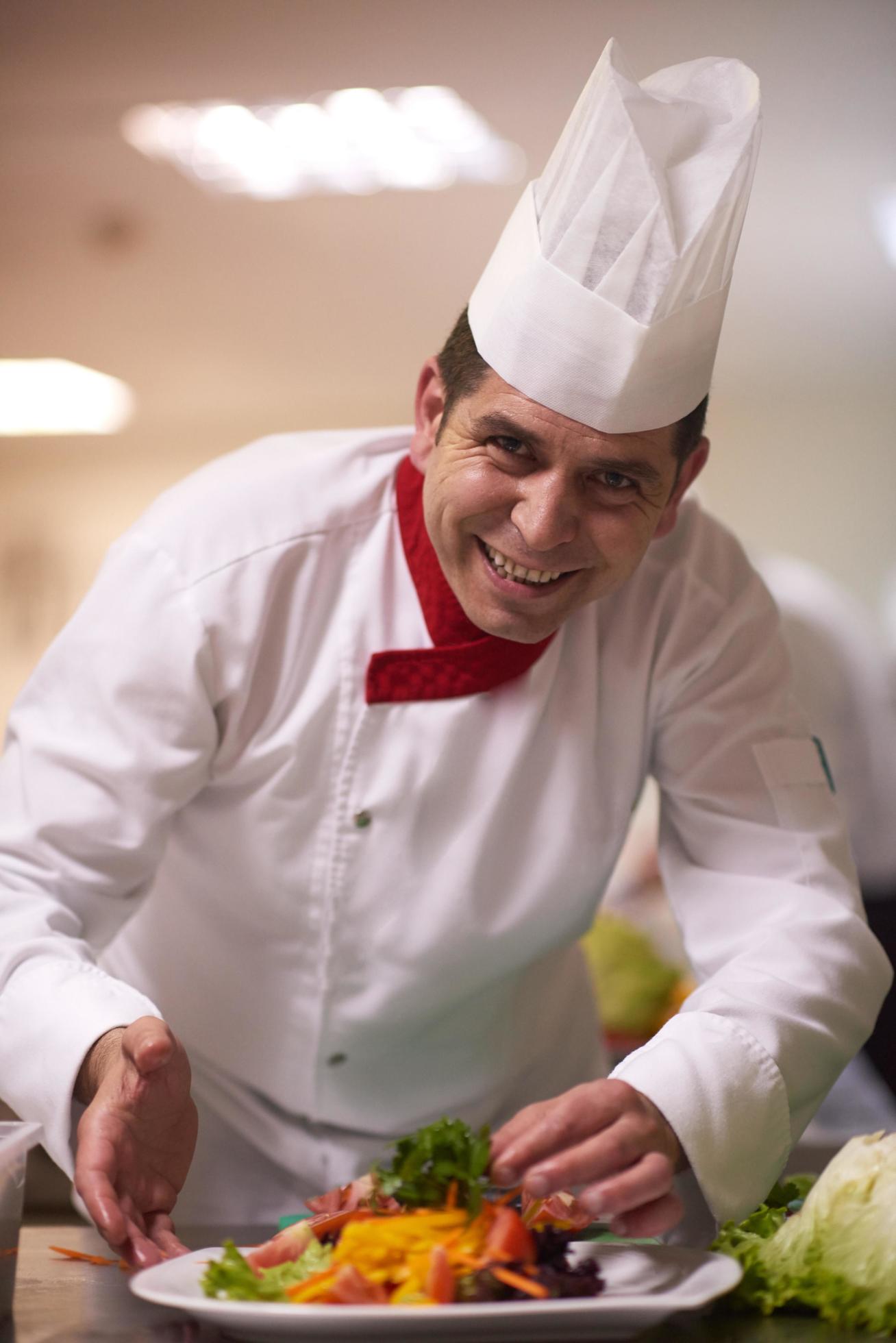 chef in hotel kitchen preparing and decorating food Stock Free