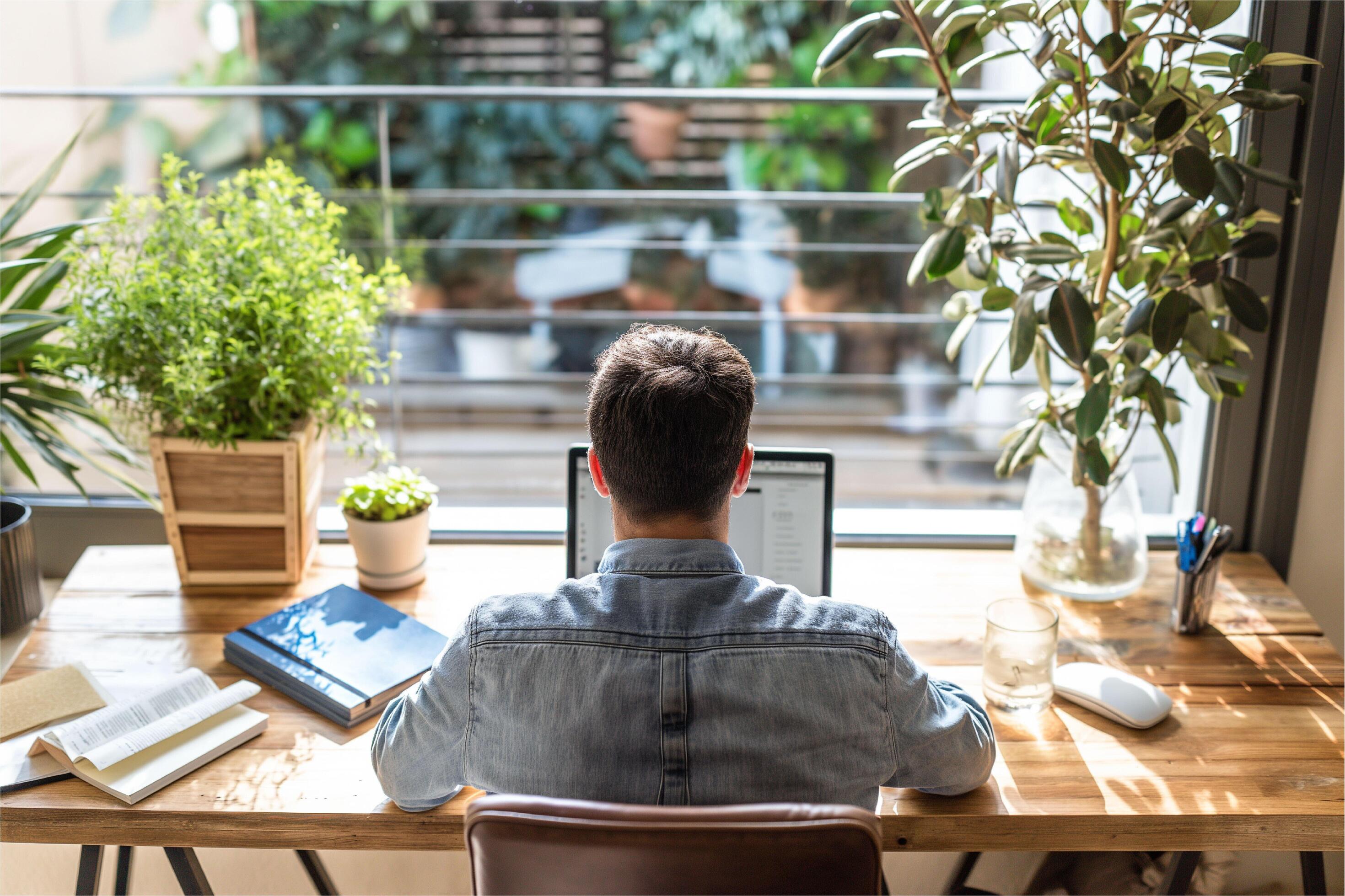 Portrait of happy arab freelancer man sitting at desk with laptop computer at home office Stock Free