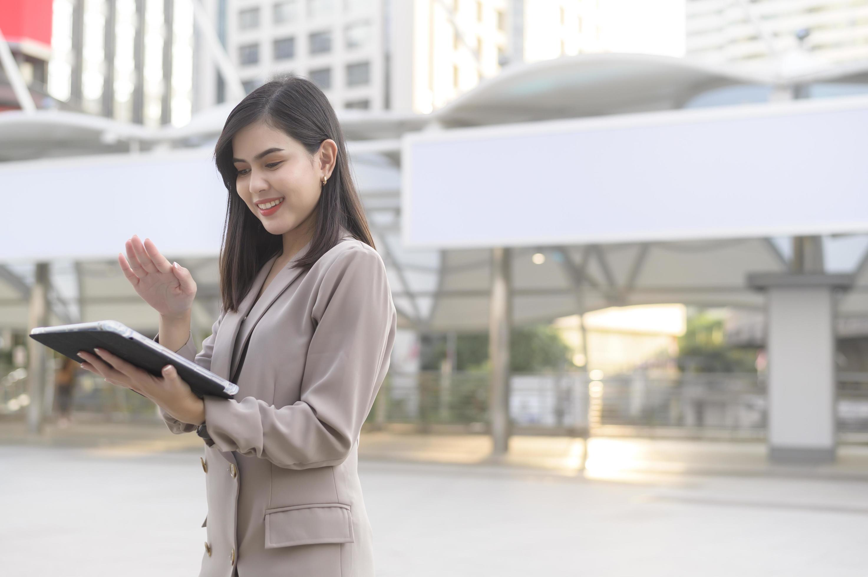 A young beautiful businesswoman is using tablet in Modern city , business technology , city lifestyle concept Stock Free