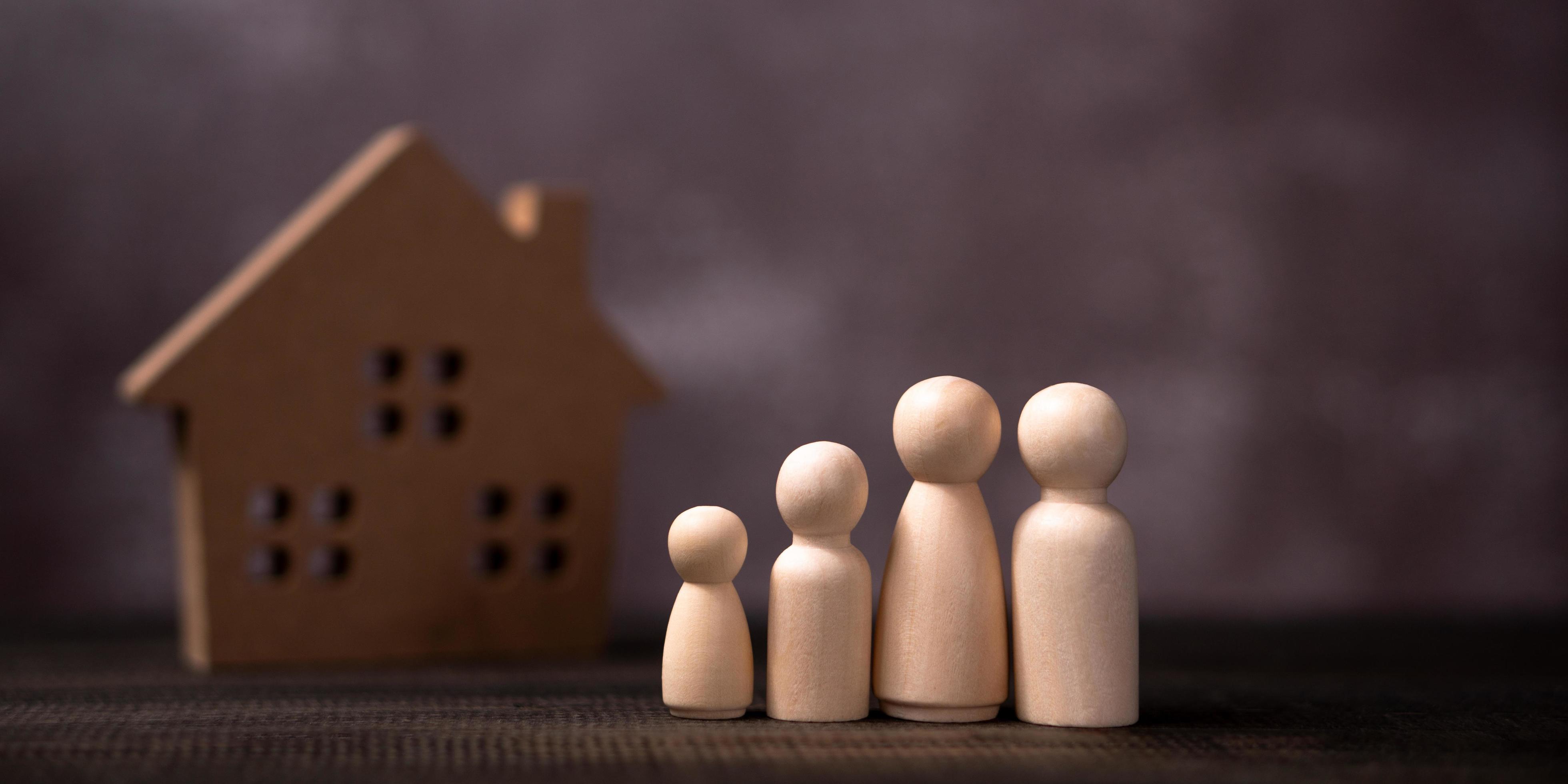 Wooden figures family standing in front of a wooden house. The concept of Protection and safety, Home Security, property insurance and house. Stock Free