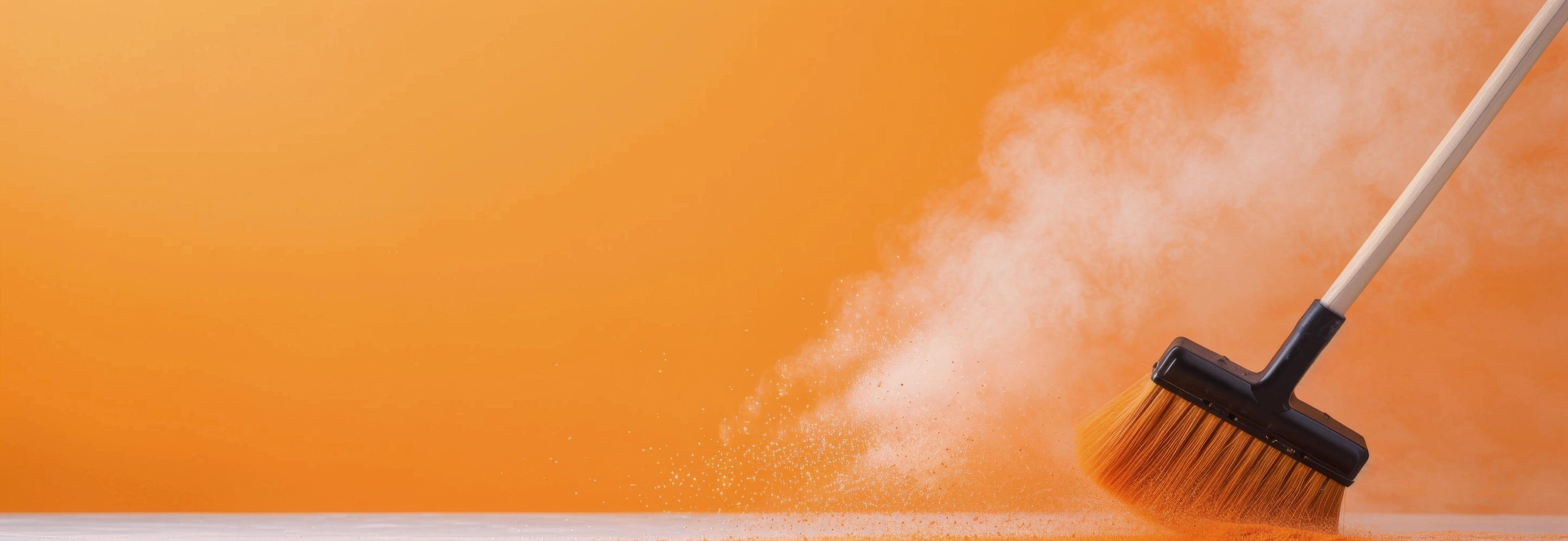 Broom Sweeping Dust on Wooden Surface With Orange Background Stock Free