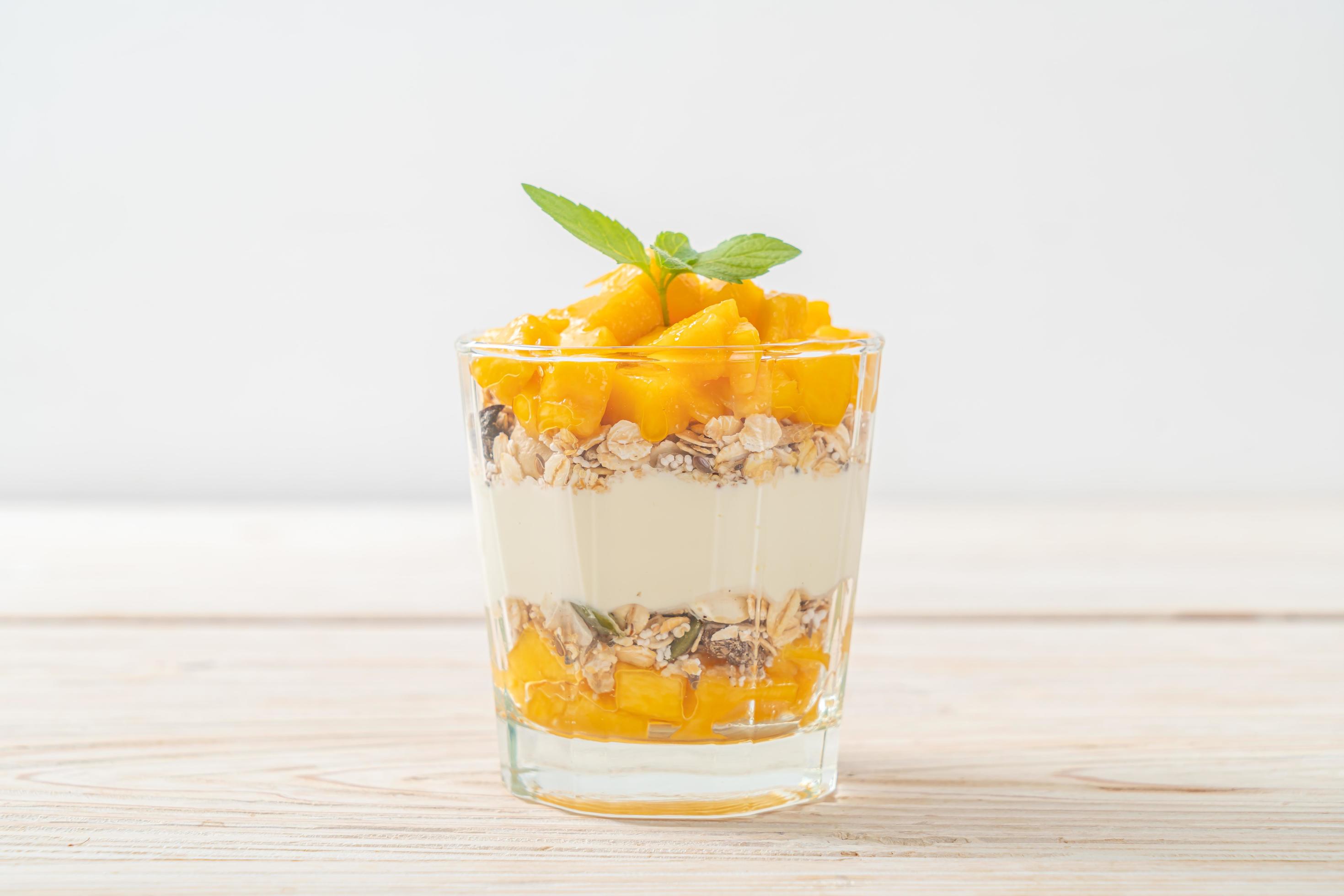 Fresh mango yogurt with granola in glass – healthy food style Stock Free