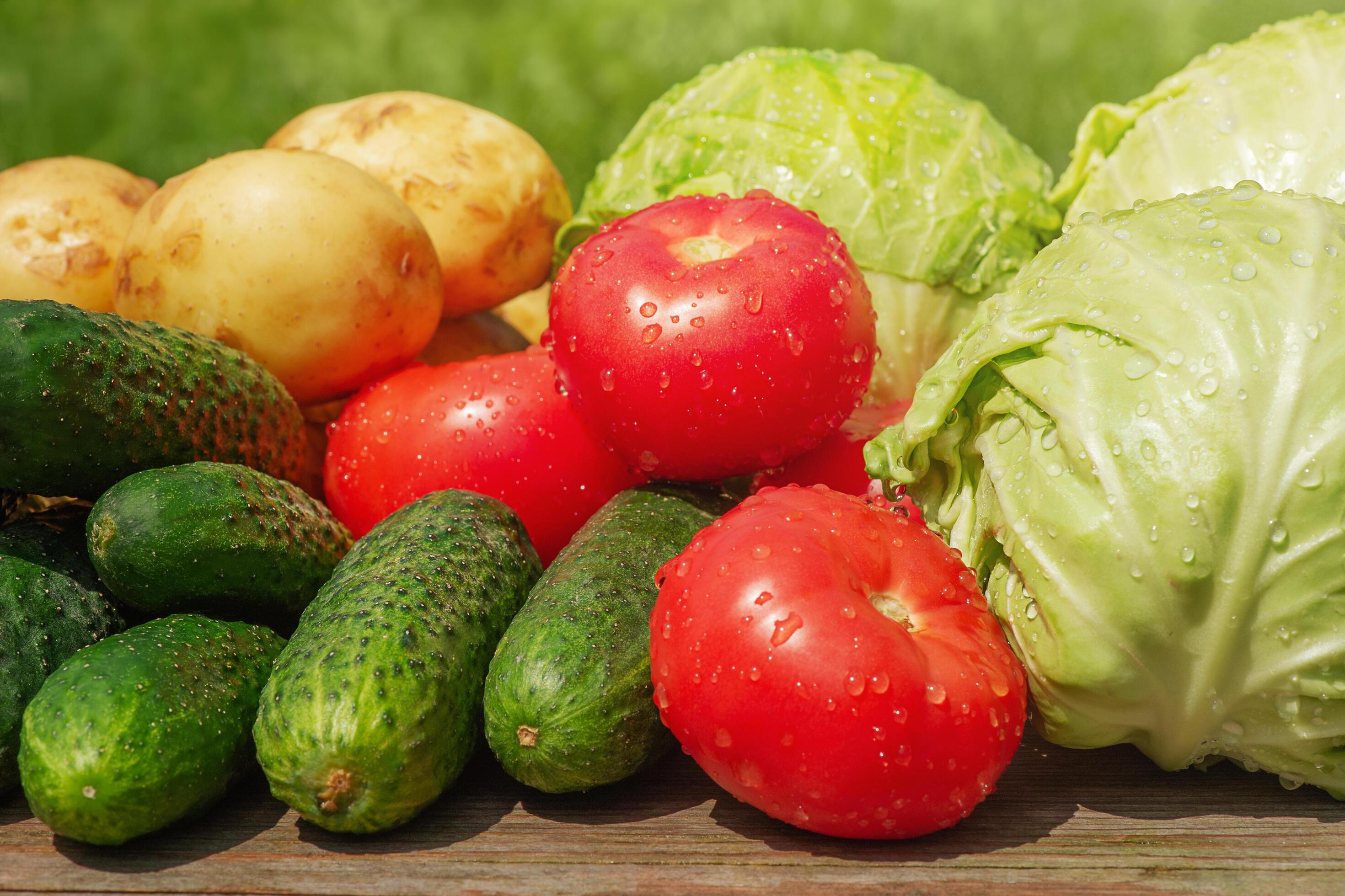 Vegetables on wooden table and with green background. Tomatoes, cucumbers, cabbages and potatoes. Stock Free