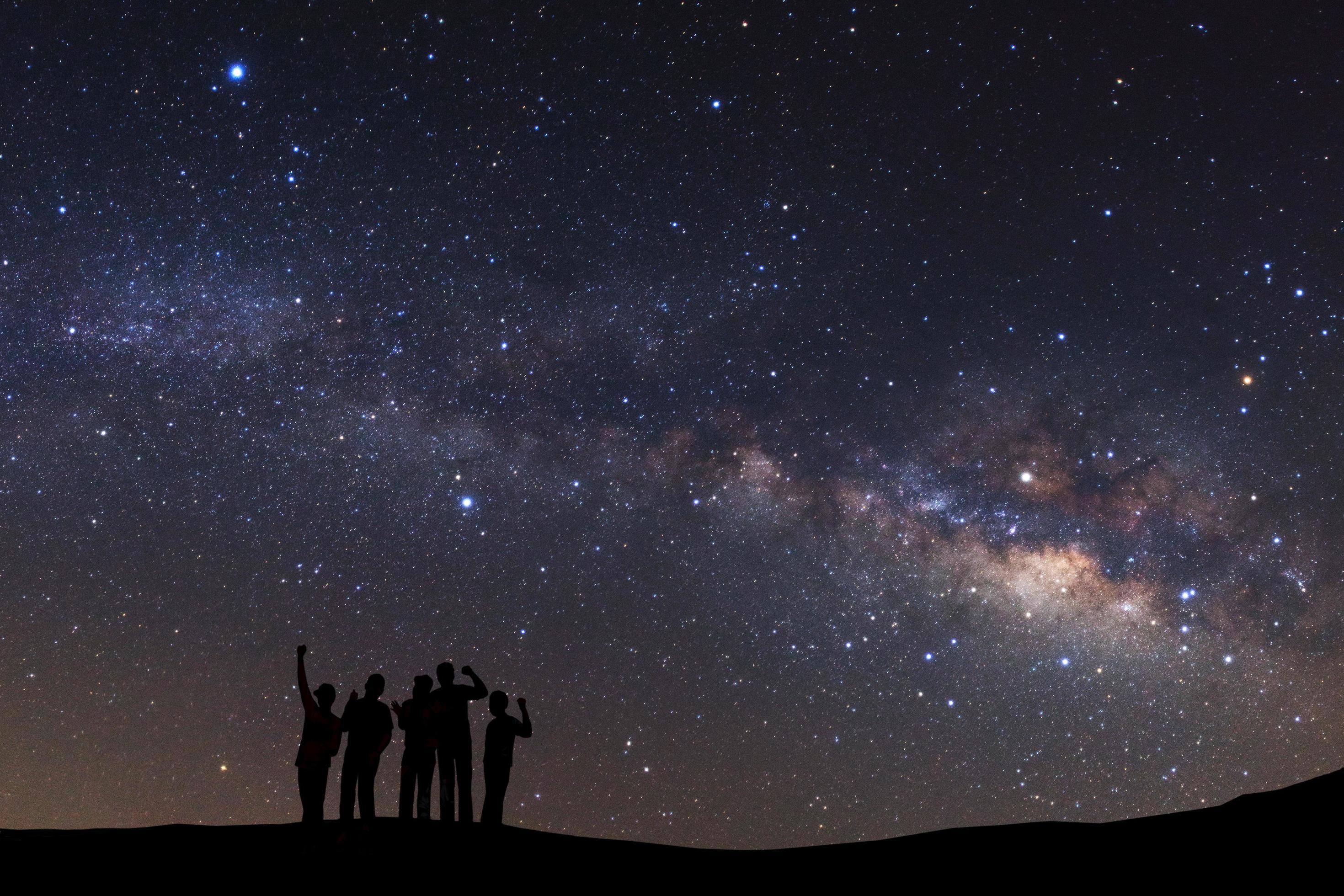 landscape with milky way, Night sky with stars and silhouette of a standing sporty man with raised up arms on high mountain. Stock Free