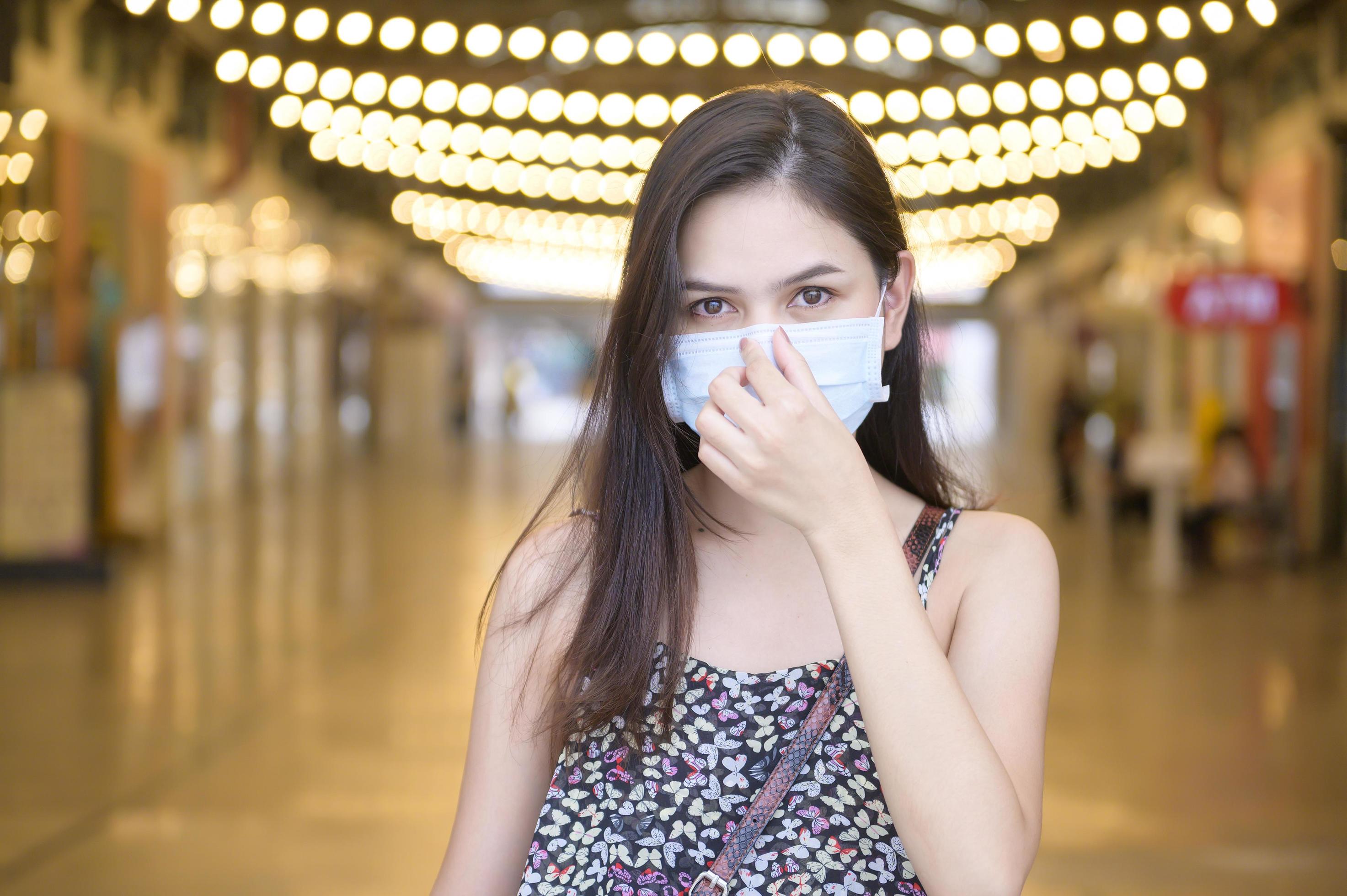 A young Asian woman is wearing protective mask shopping in shopping center, Coronavirus protection,New normal lifestyle concept Stock Free