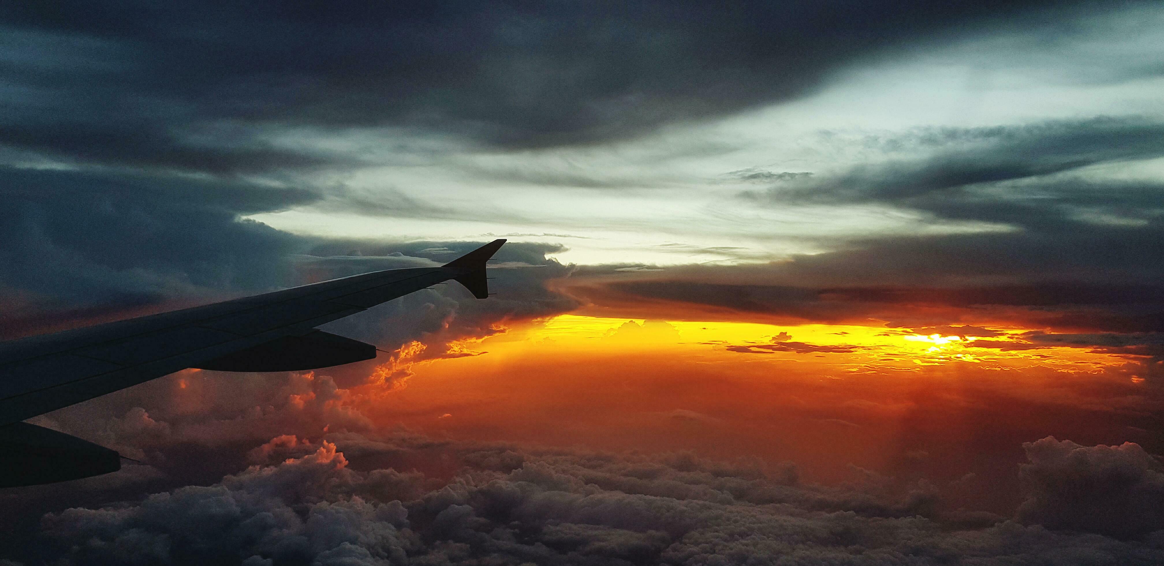 Silhouette of aircraft or airplane wing on dark sky with sunset light flare background. Transportation, Travel and Beauty of Nature concept Stock Free