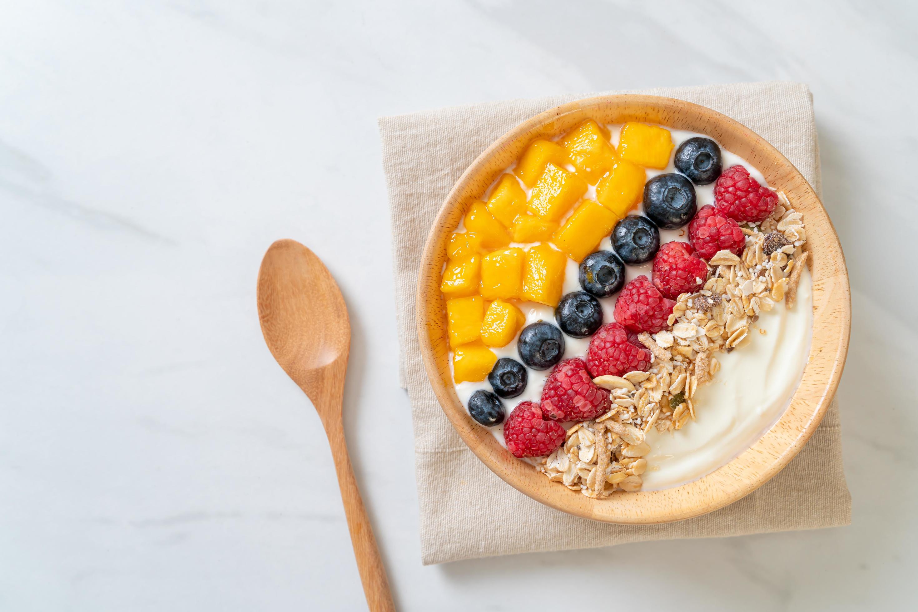 Homemade yogurt bowl with raspberry, blueberry, mango, and granola – healthy food style Stock Free