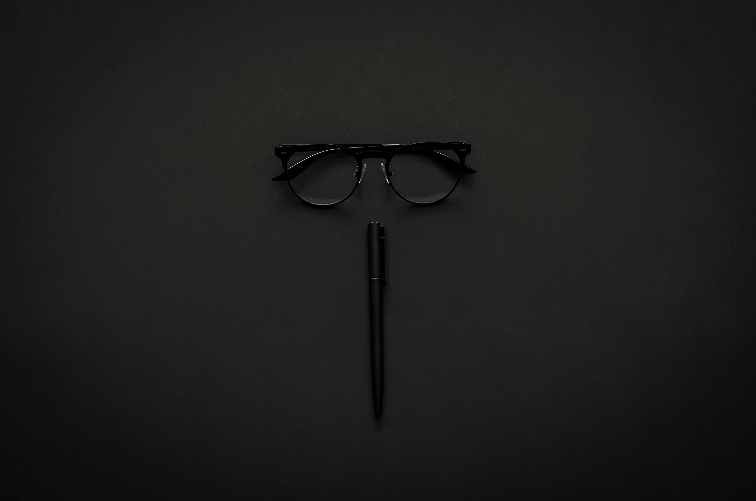 
									Eyeglasses and pen in modern lifestyle on dark background for minimalist flat lay black concept. Stock Free