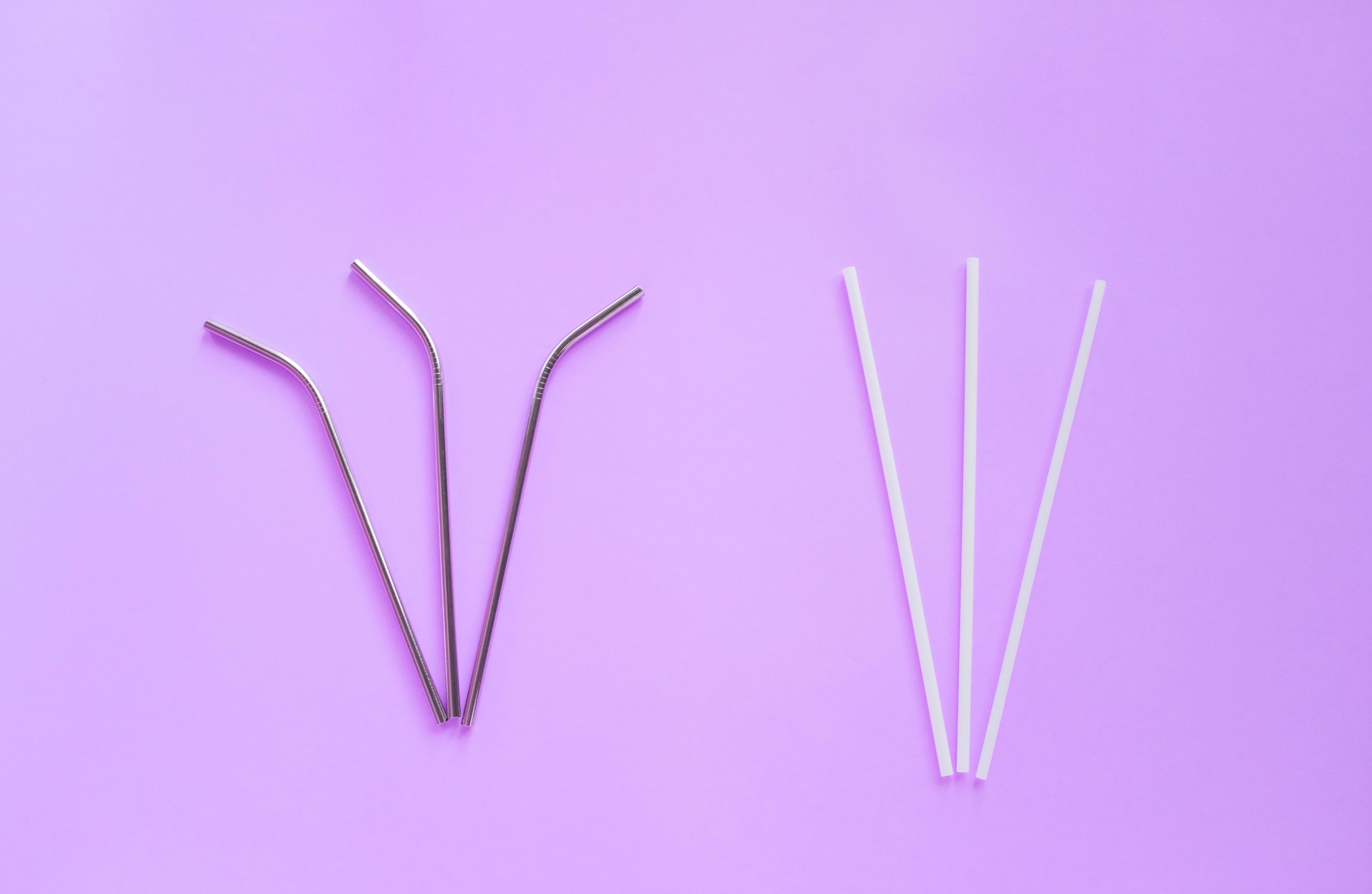 Flat lay of reusable stainless steel straw with plastic straw on bright purple color background, sustainable lifestyle and zero waste concept Stock Free