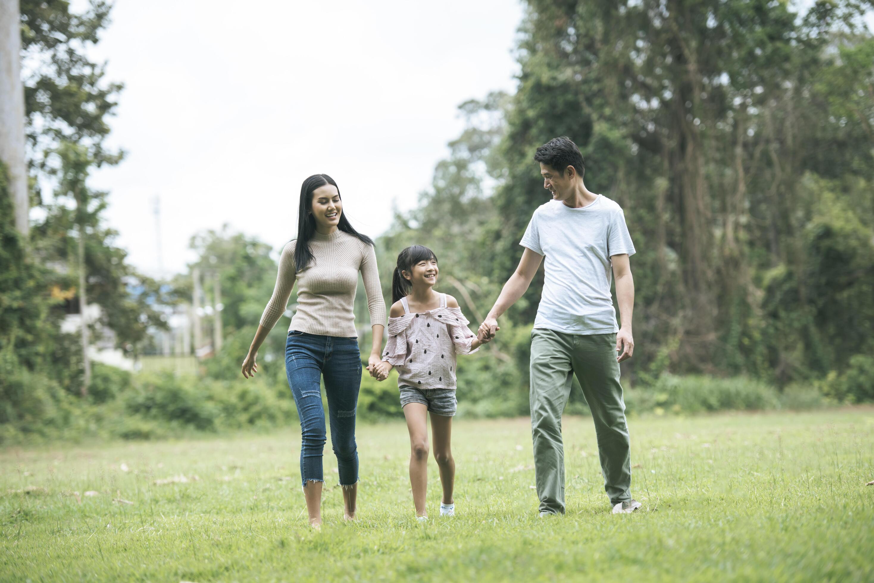 Happy parents and their daughter walking in the park, Happy family concept. Stock Free