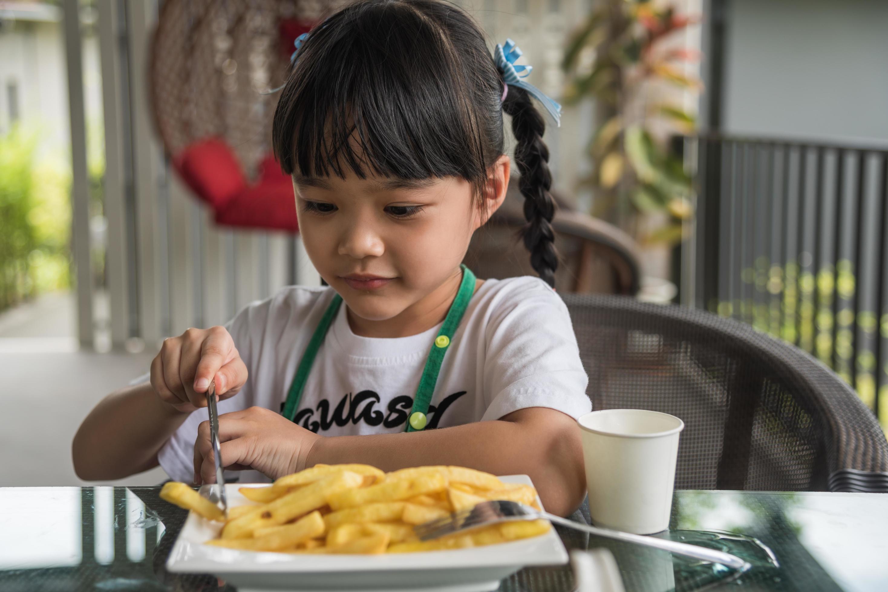 Young Asian girl eating french fries young kid fun happy potato fast food. Stock Free