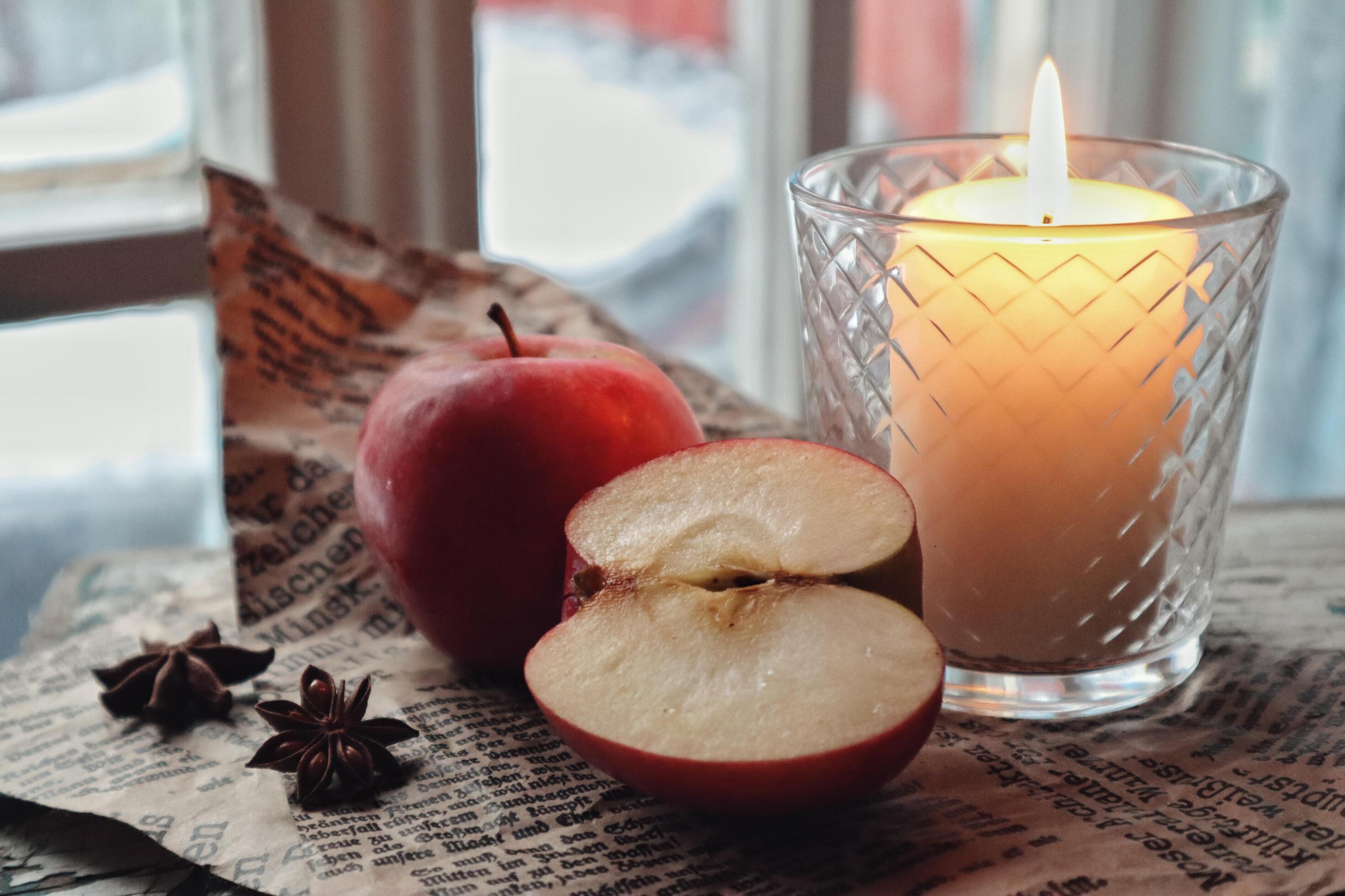 Cozy still life food photography Red apples cut half with anise spices on a craft paper next to a candle Stock Free