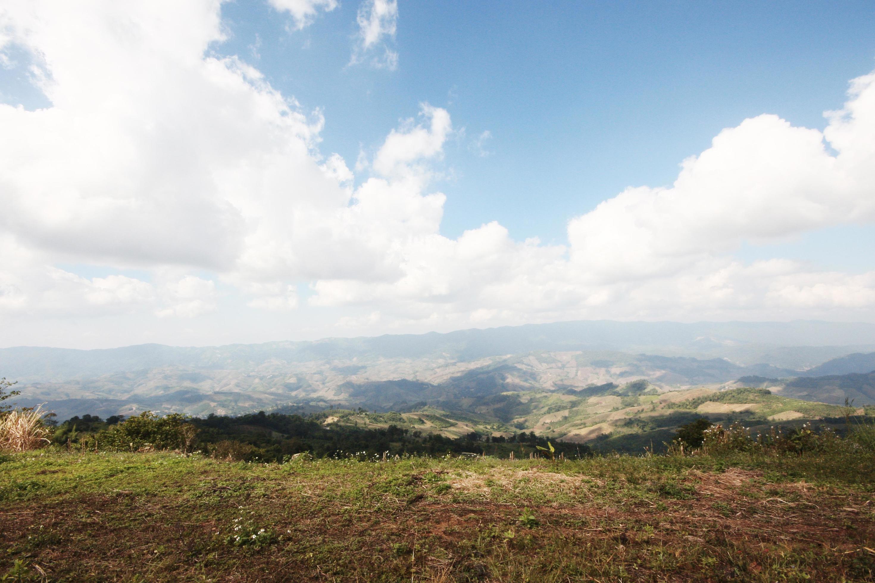 Aerial view of hightland with dry grass and forest hill in blue sky on the valley mountain in Thailand Stock Free