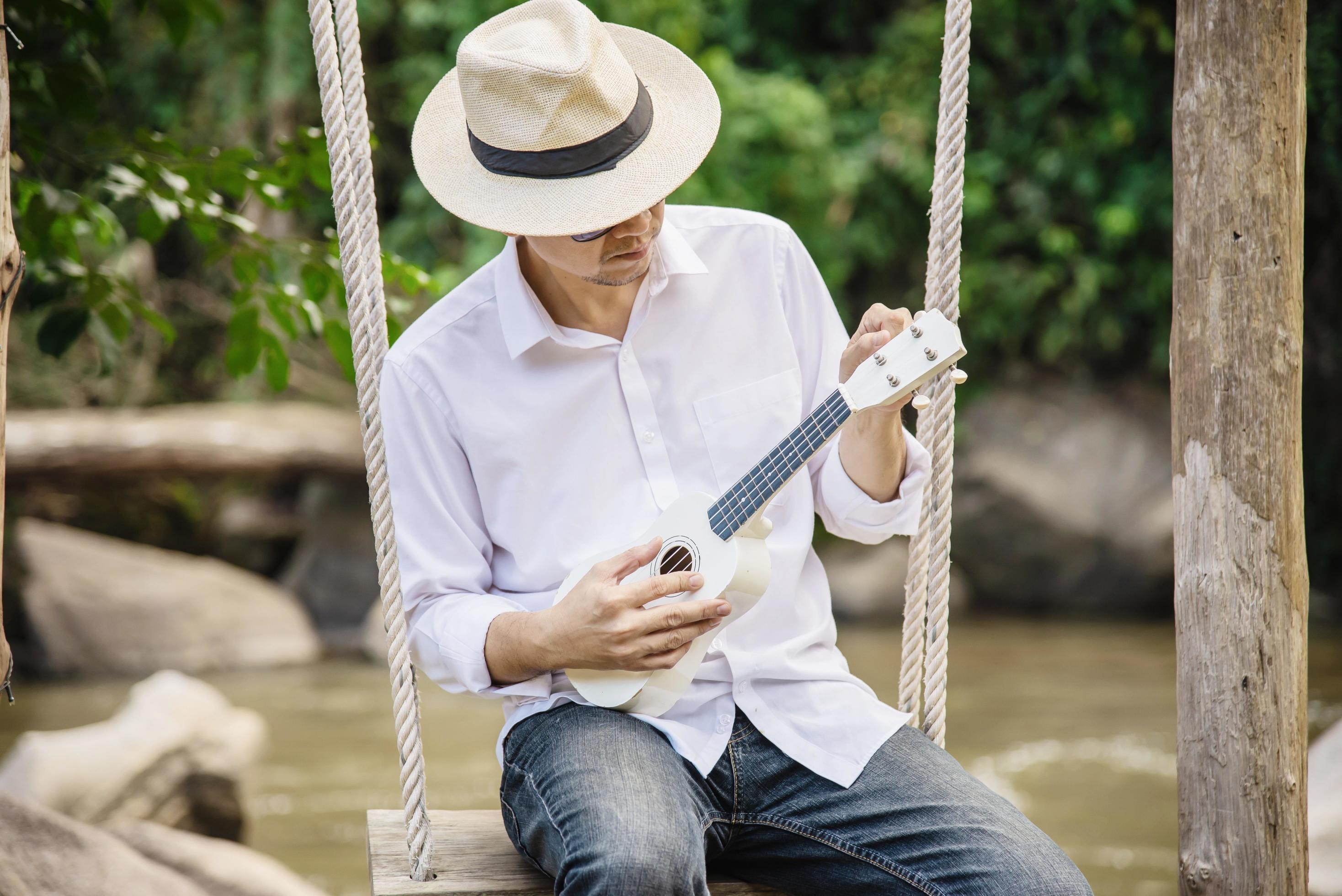 Man play ukulele new to the river- people and music instrument life style in nature concept Stock Free