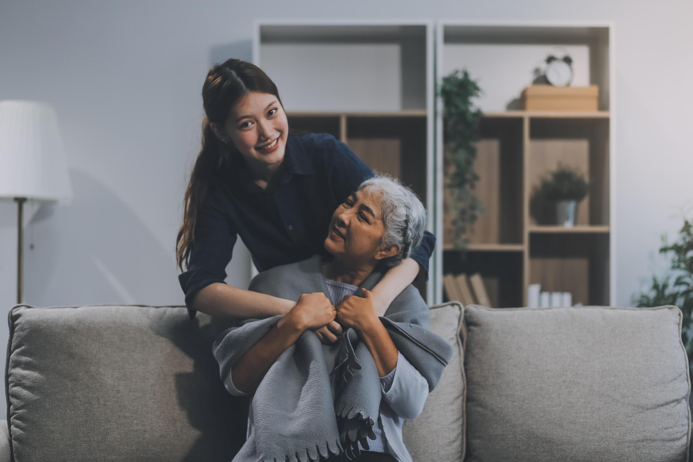 happy family Granddaughter takes care of her grandmother with warm cloths sitting on the sofa. Stock Free