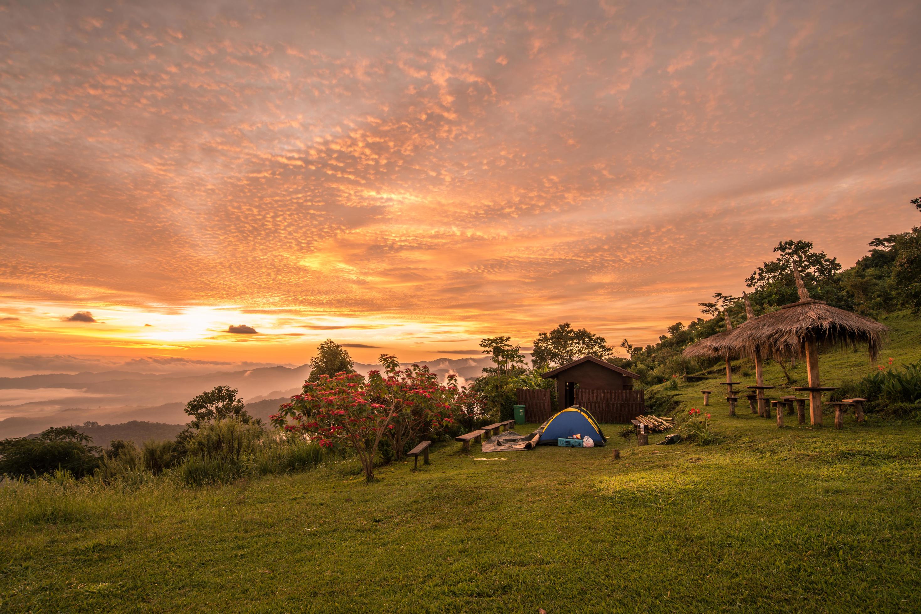 Dramatic sky at sunrise with camping tent on Doi Kart Phee the remote highland mountains area in Chiang Rai province of Thailand. Stock Free