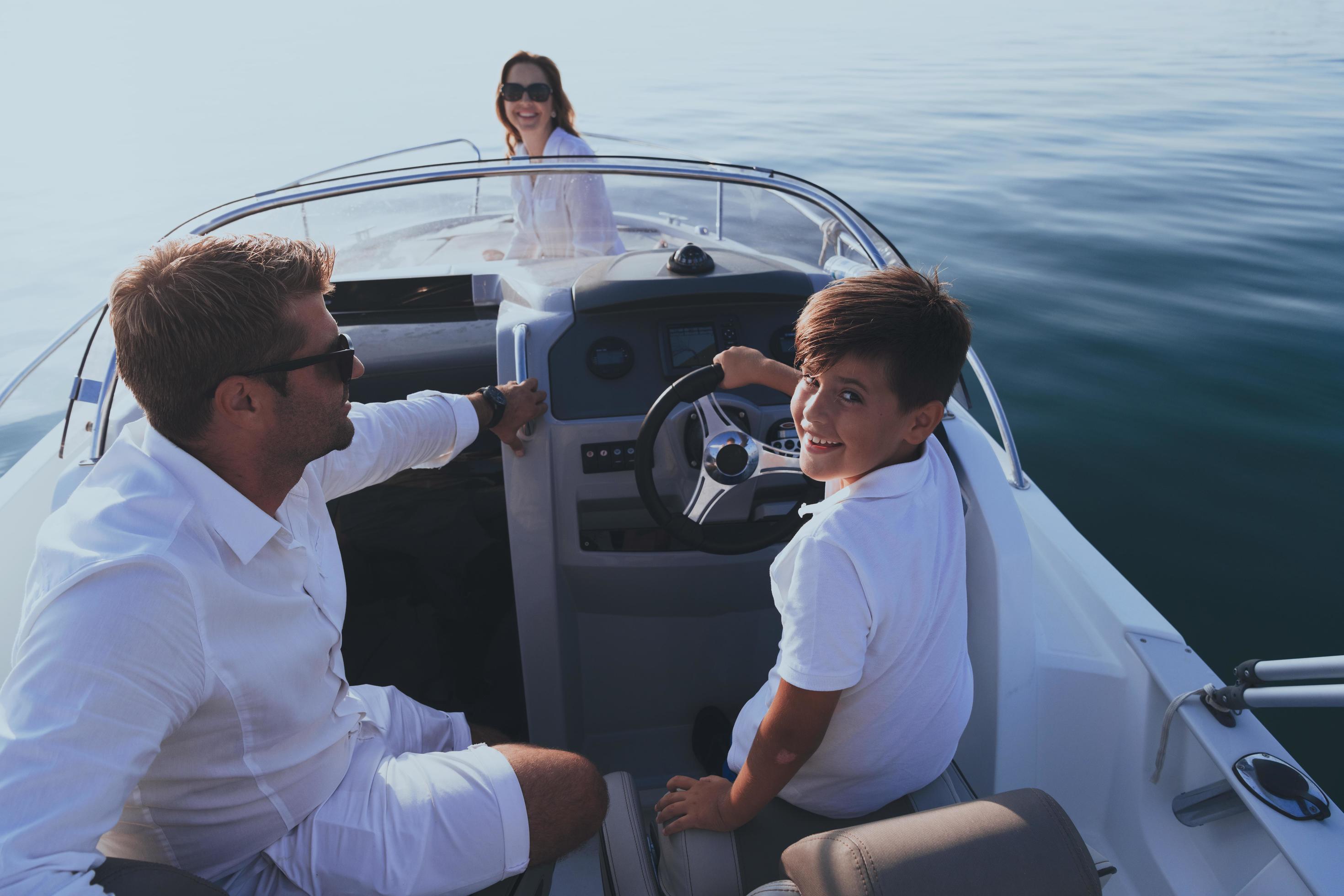 A senior couple in casual outfits with their son enjoy while riding a boat at sea at sunset. The concept of a happy family. Selective focus Stock Free