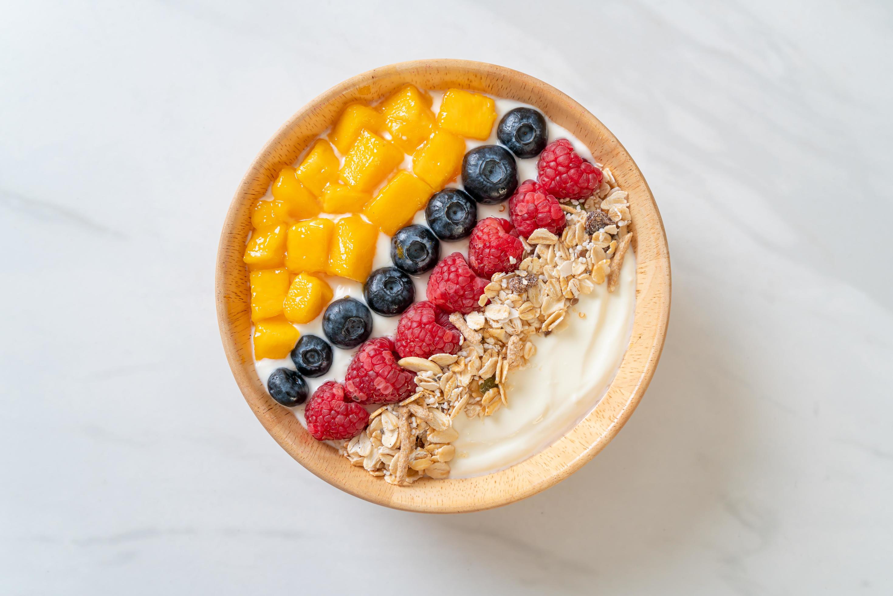 Homemade yogurt bowl with raspberry, blueberry, mango, and granola – healthy food style Stock Free